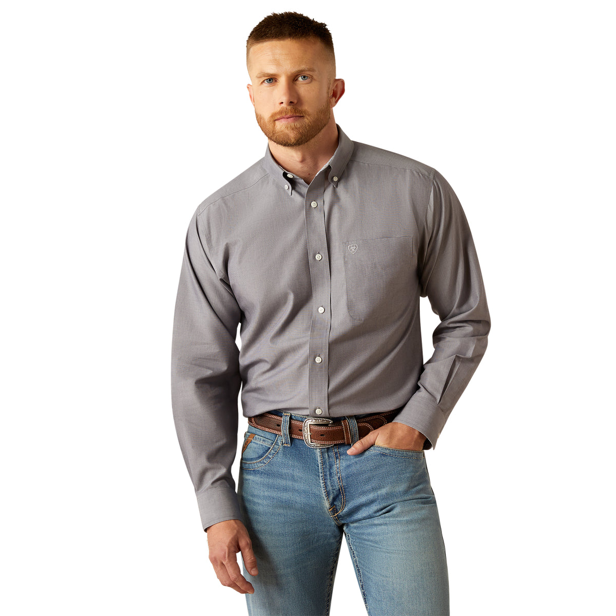 Ariat Men&#39;s Wrinkle Free Solid L/S Western Shirt. Man wearing a gray button-up shirt and blue jeans on a white background