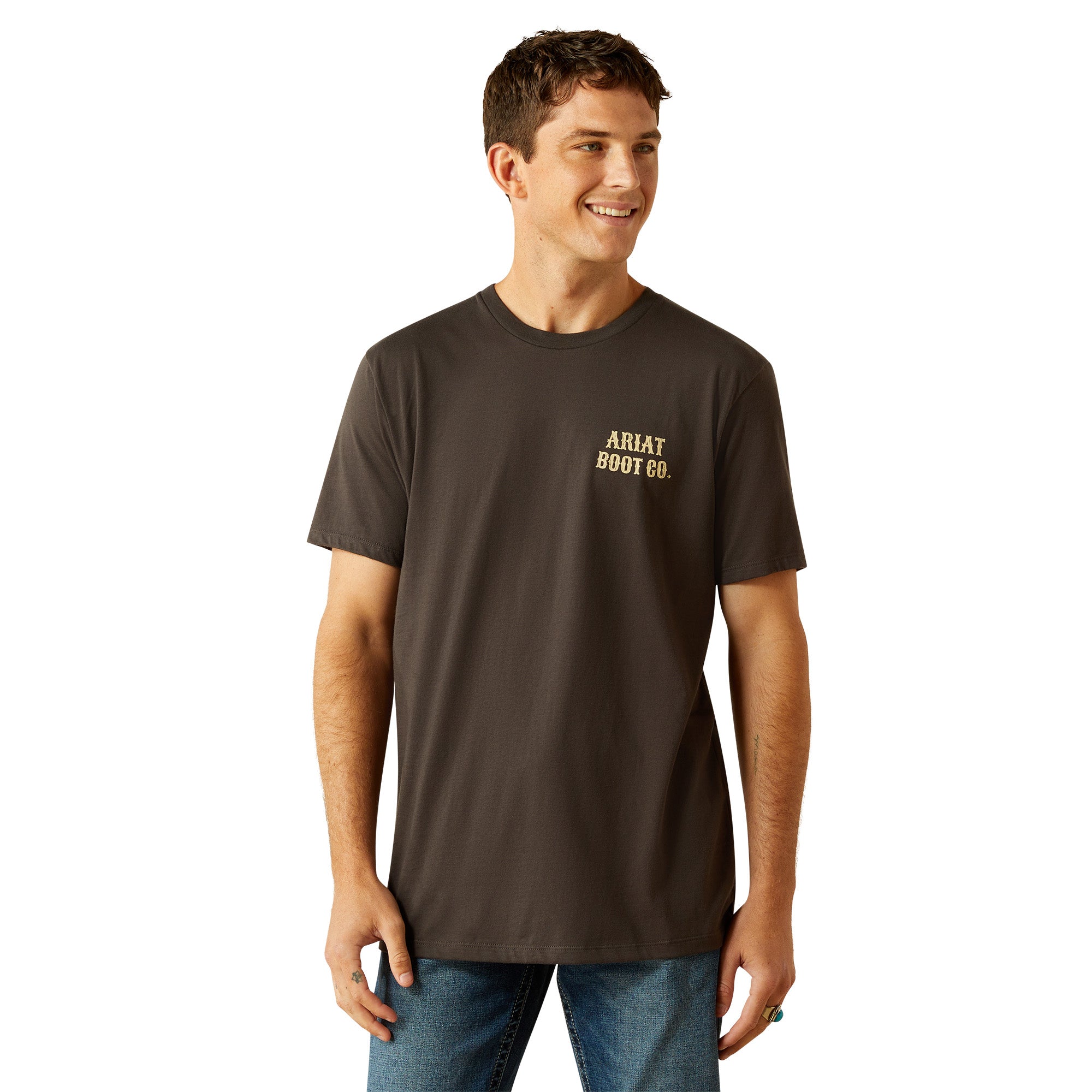 Ariat Men's Cowboy Cocky T-Shirt. Man wearing a dark brown t-shirt with a colorful rooster graphic and 'Cocky Cowboy' text on the back.