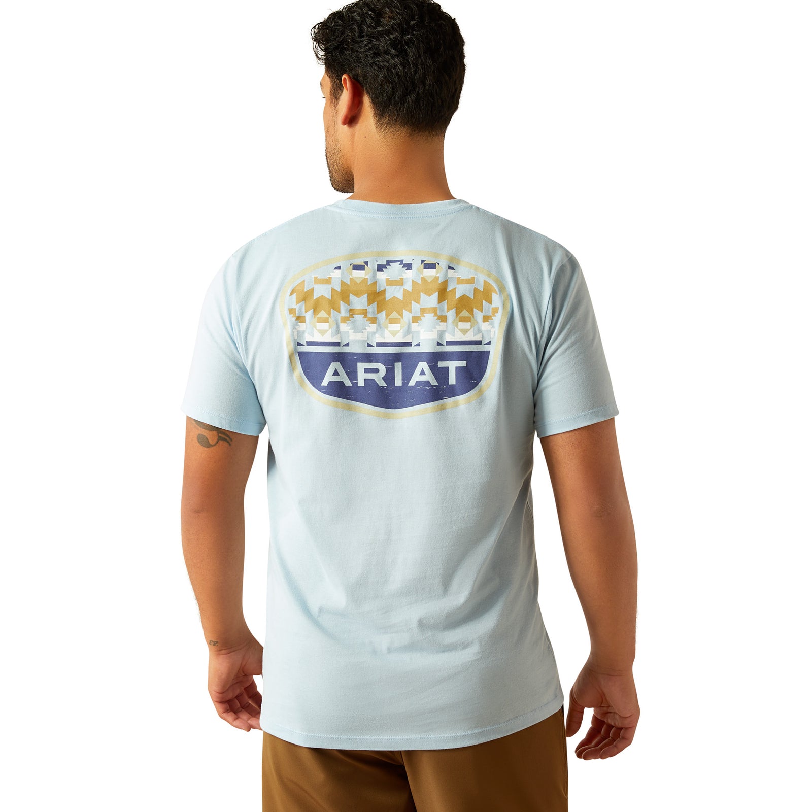 Ariat Men's Ogden Valley Badge T-Shirt. Person wearing a light blue t-shirt with Ariat logo on the back