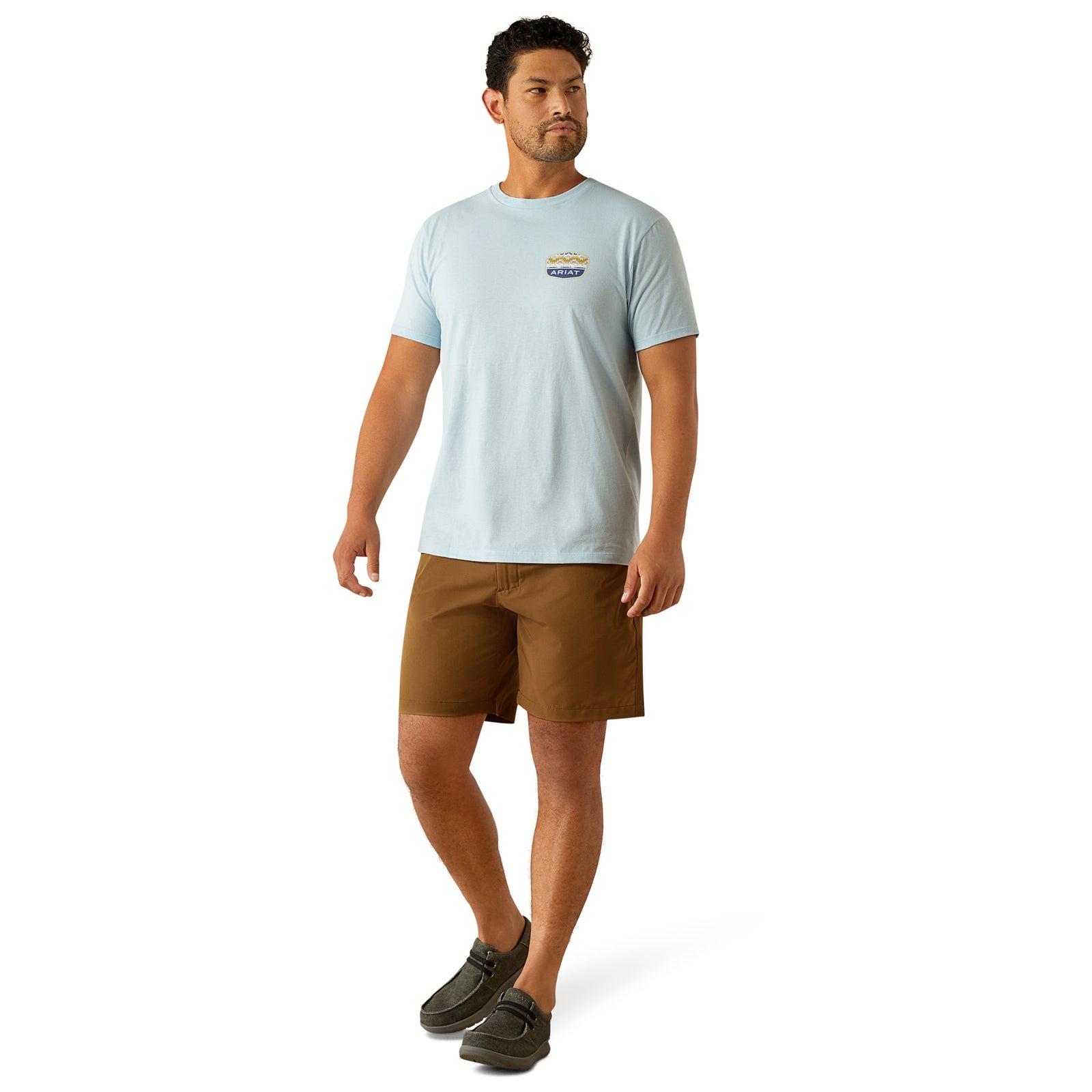 Ariat Men's Ogden Valley Badge T-Shirt. Man wearing a light blue t-shirt and brown shorts on a white background