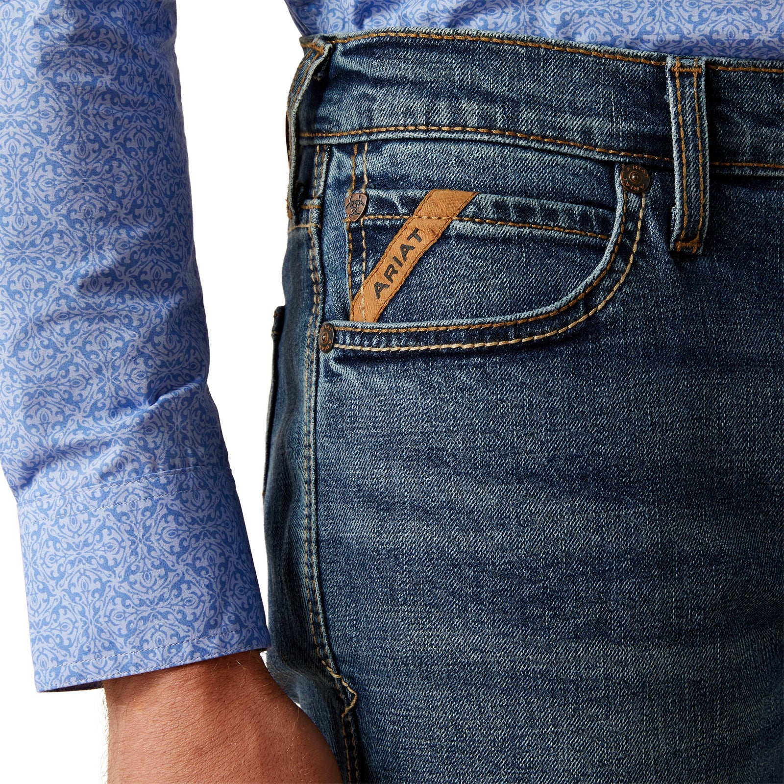 Ariat Men's M8 Miles Modern Fit Jean. Close-up of blue jeans with ARIAT logo on a white background