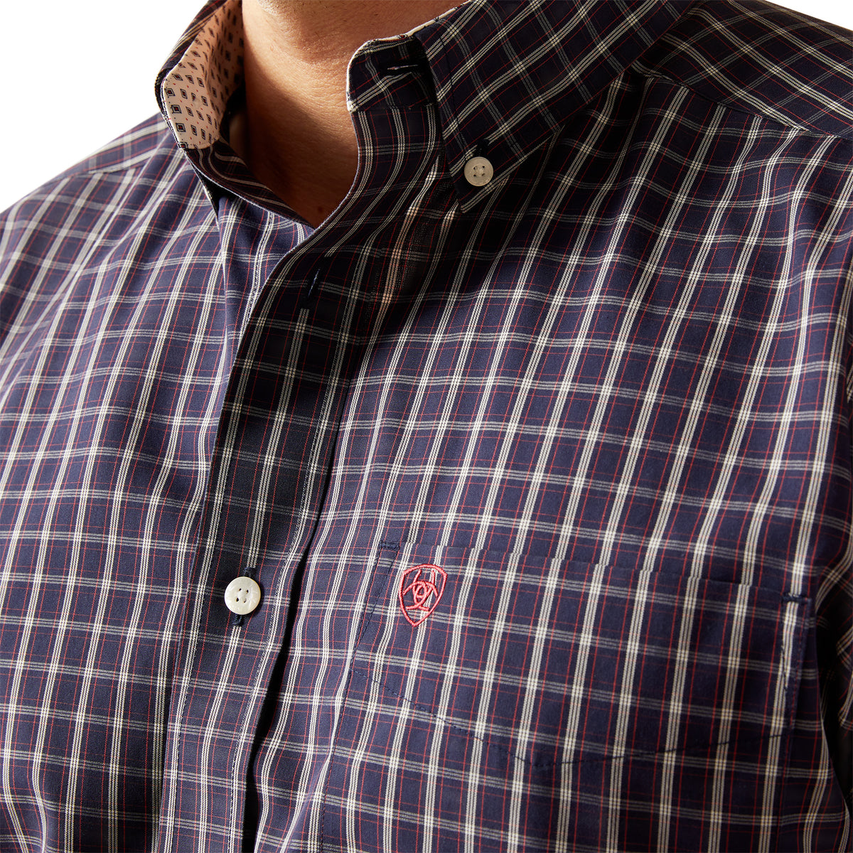 Ariat Men's Wrinkle Free Dwayne L/S Western Shirt. Close-up of a checkered shirt with a brand logo on a plain background