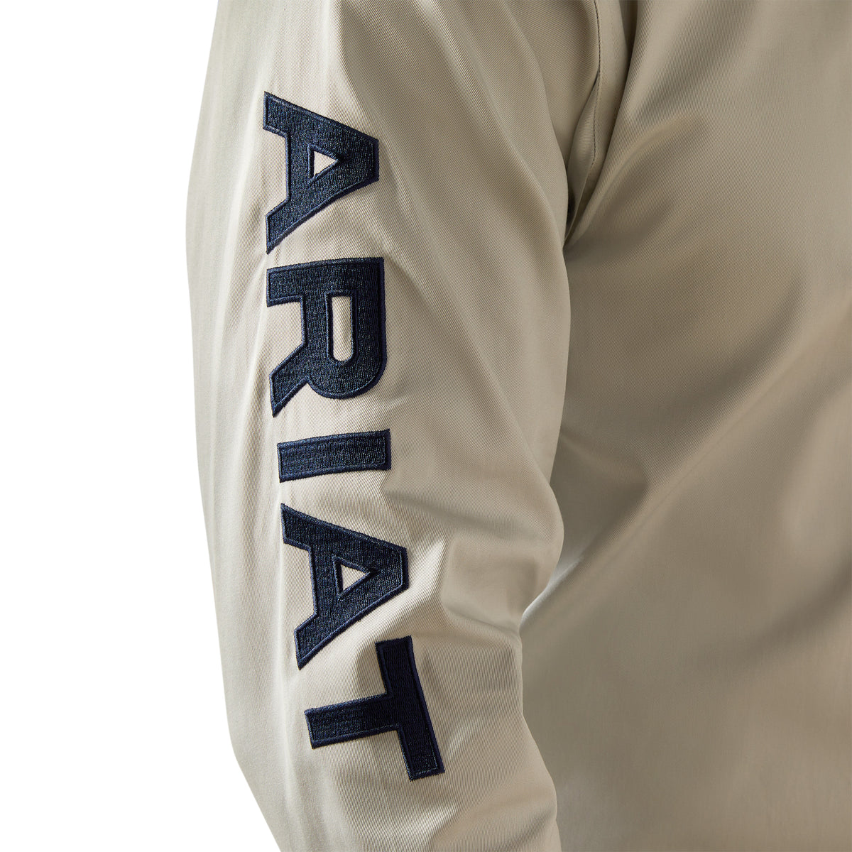 Ariat Men's Team Logo Twill L/S Western Shirt. Beige long-sleeve shirt with 'ARIAT' branding on a white background