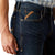 Ariat Men's M4 Otis Boot Cut Jean. Close-up of a person wearing blue jeans with Ariat branding on a white background