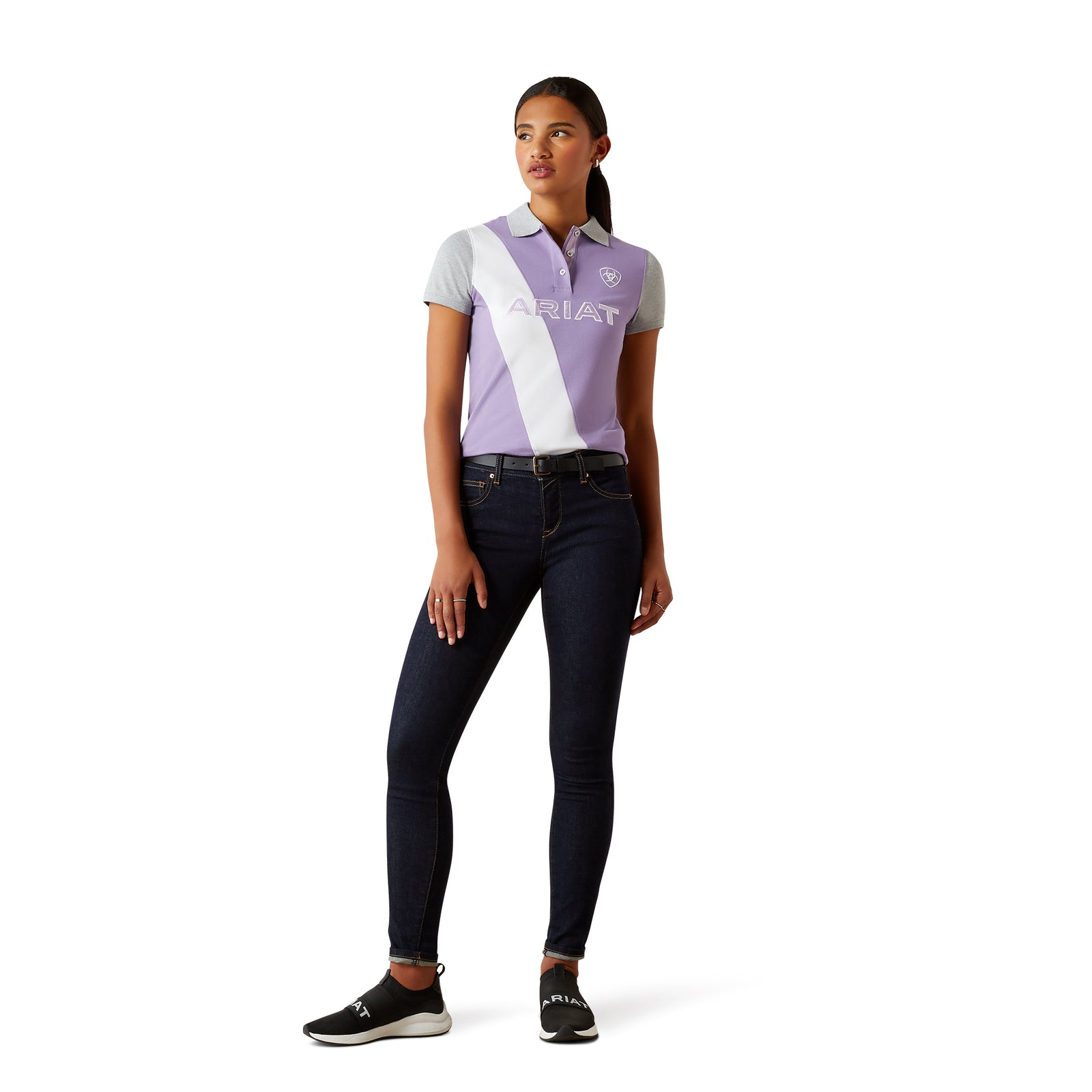 Ariat Women's Taryn Polo. Woman wearing a polo shirt and jeans with a visible brand logo on a white background