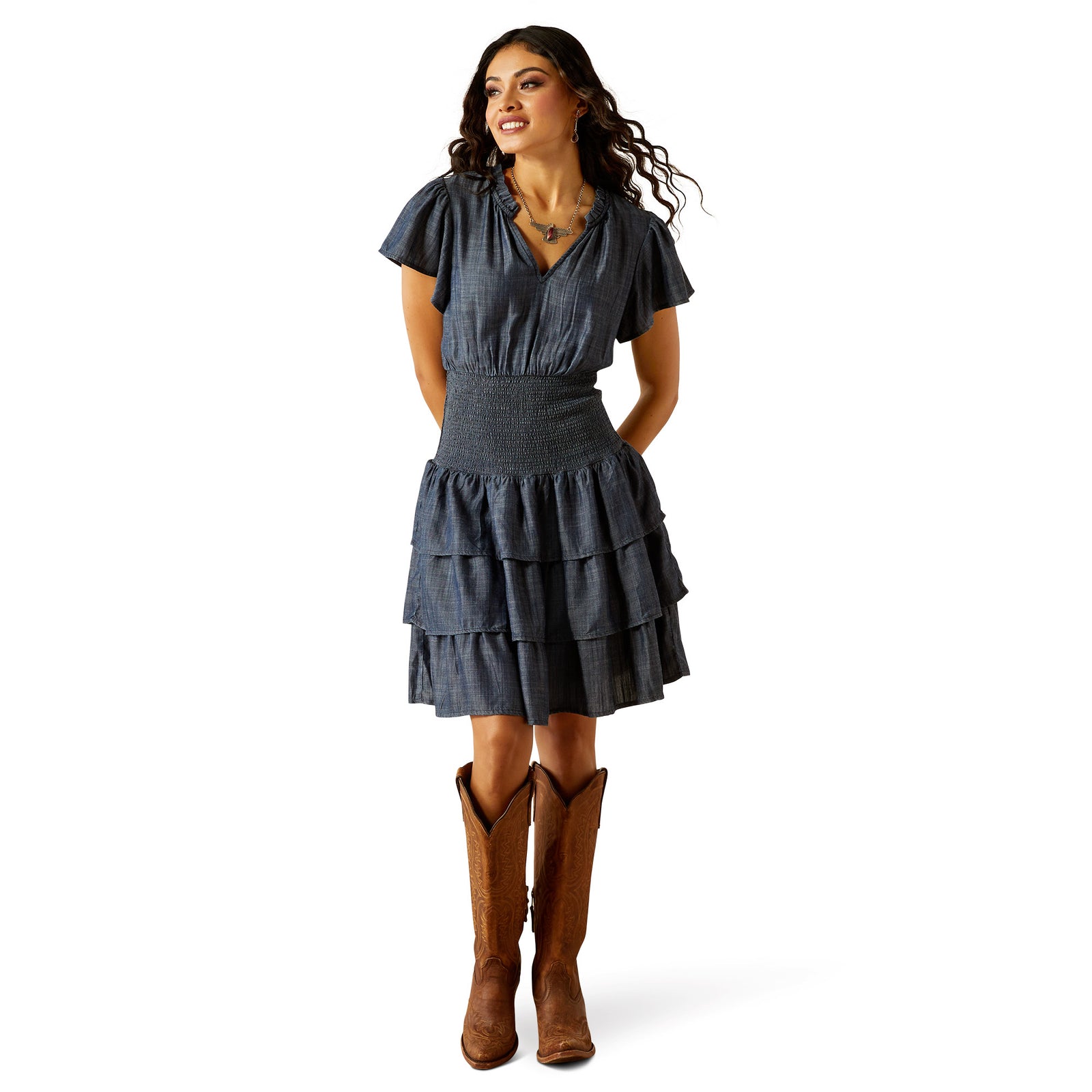 Ariat Women's Stellar Dress. Woman wearing a denim dress and brown boots on a white background