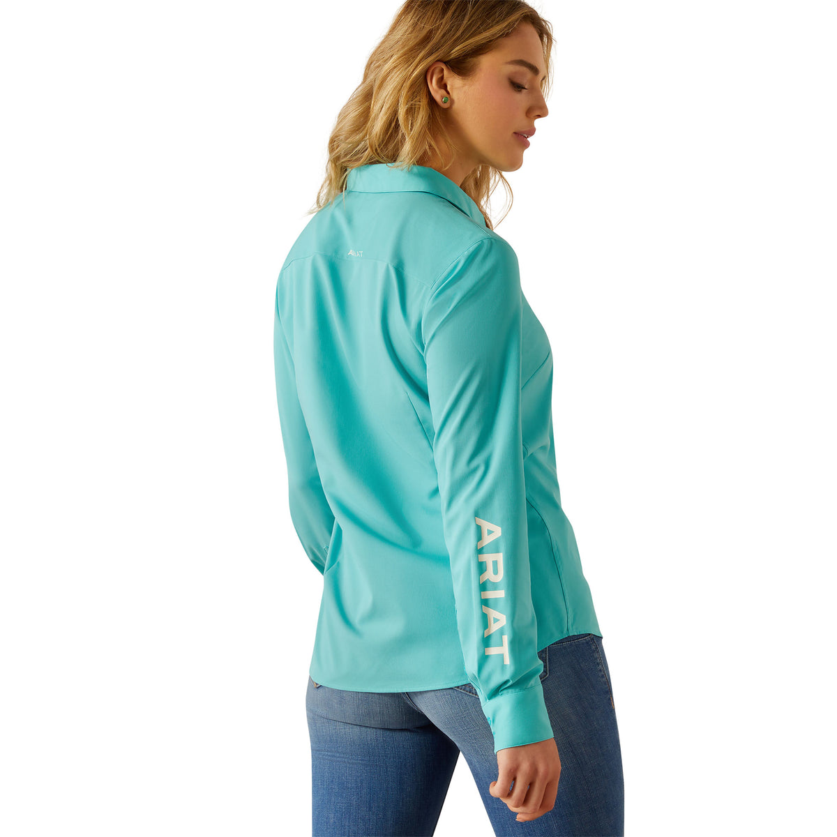 Ariat Women's Kirby Pro L/S Western Shirt. Woman wearing a teal long-sleeve shirt with 'Ariat' branding on a white background