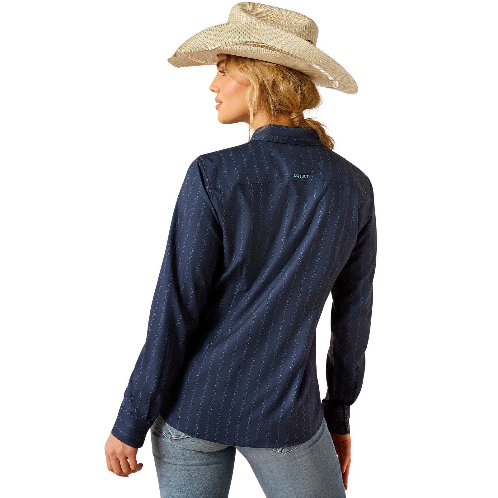 Ariat Women's Kirby Pro L/S Western Shirt. Woman wearing a blue denim shirt with 'Ariat' branding, jeans, and a cowboy hat on a white background