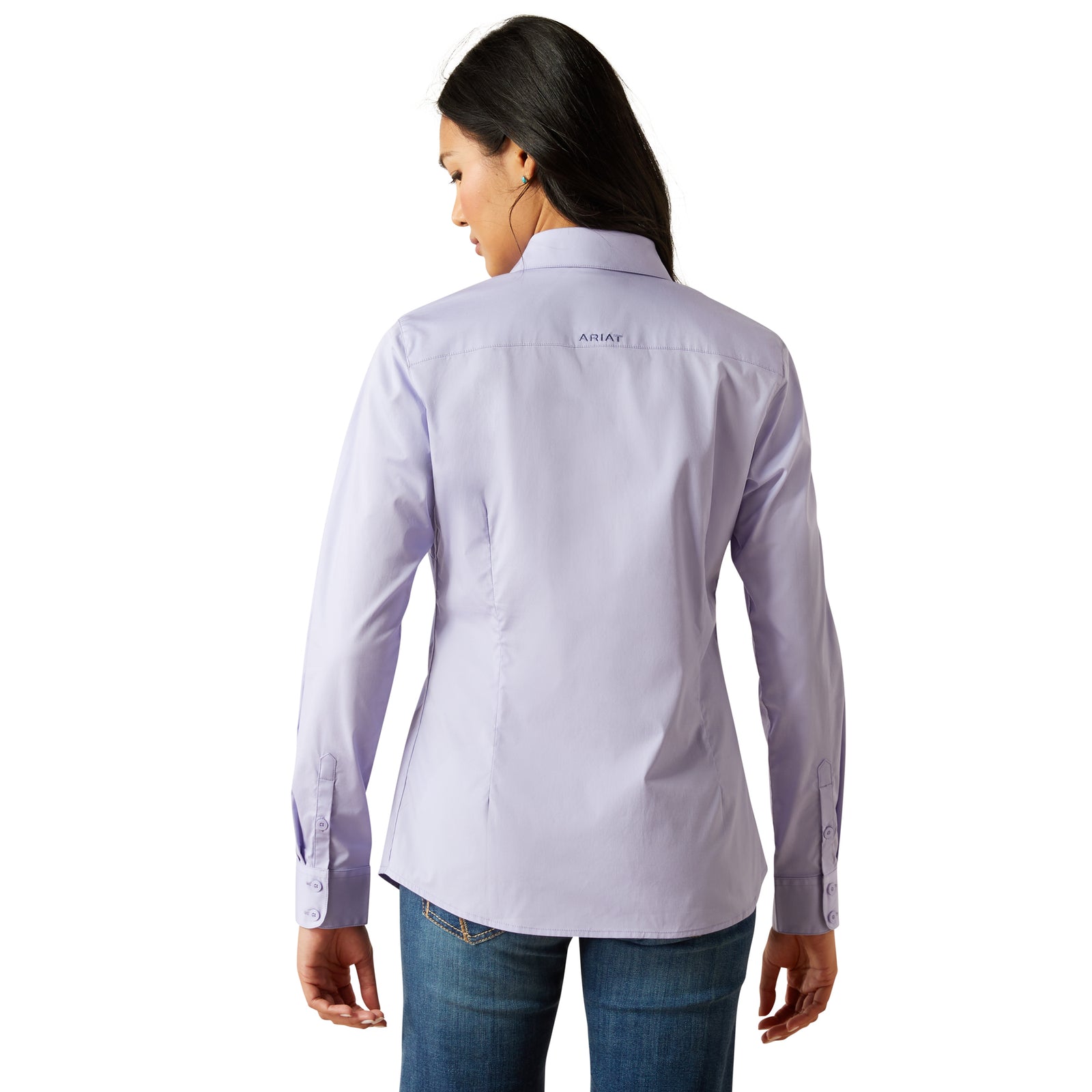 Ariat Women's Wrinkle Resistant Team Kirby L/S Western Shirt. Woman wearing a light purple shirt with a brand logo on the back, standing against a white background.