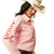 Ariat Women's Wrinkle Resistant Team Kirby Western Shirt. Person wearing a pink striped shirt with 'Riviera' branding and a cowboy hat on a white background