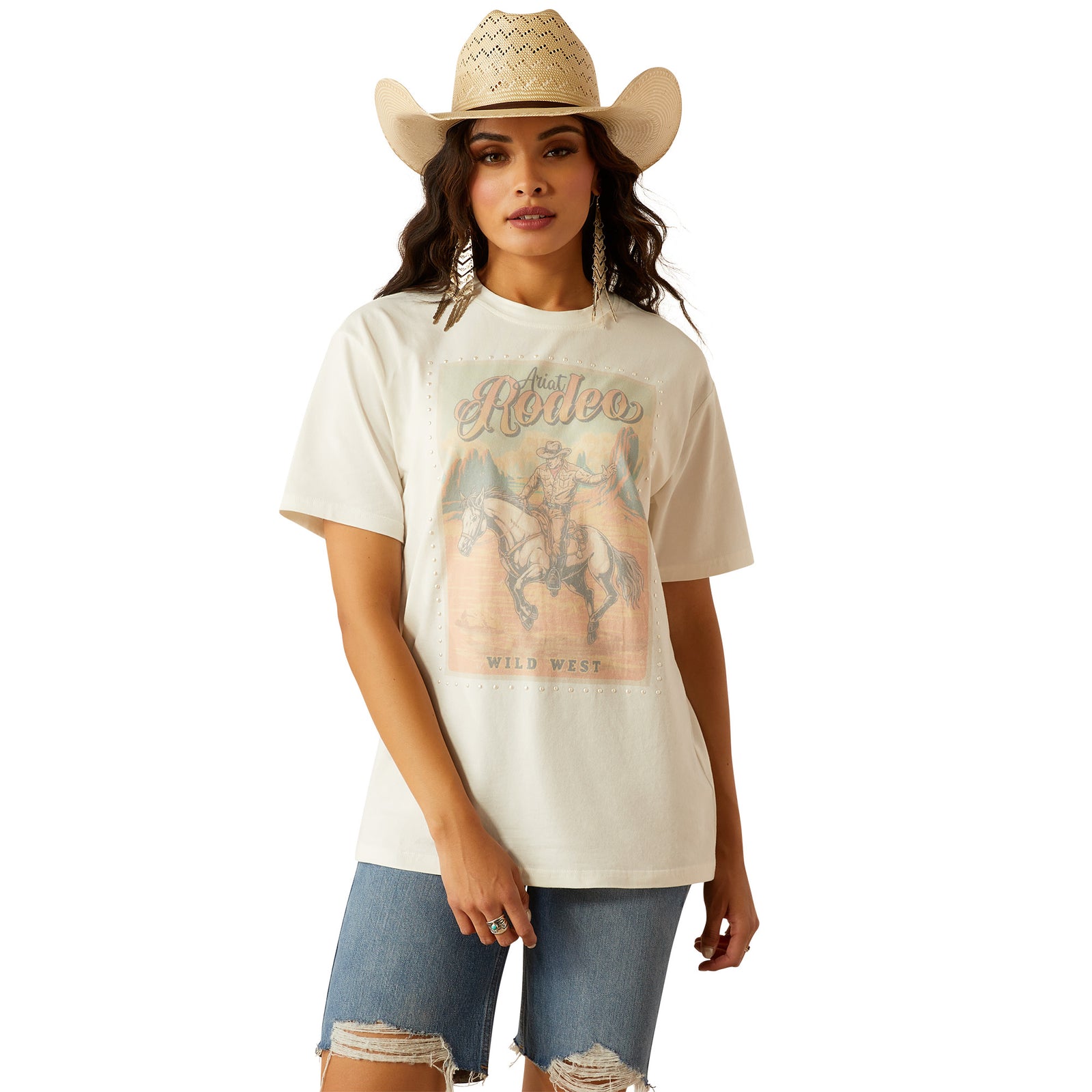 Ariat Women's Rodeo T-Shirt. Woman wearing a white t-shirt with a graphic design and a cowboy hat on a white background