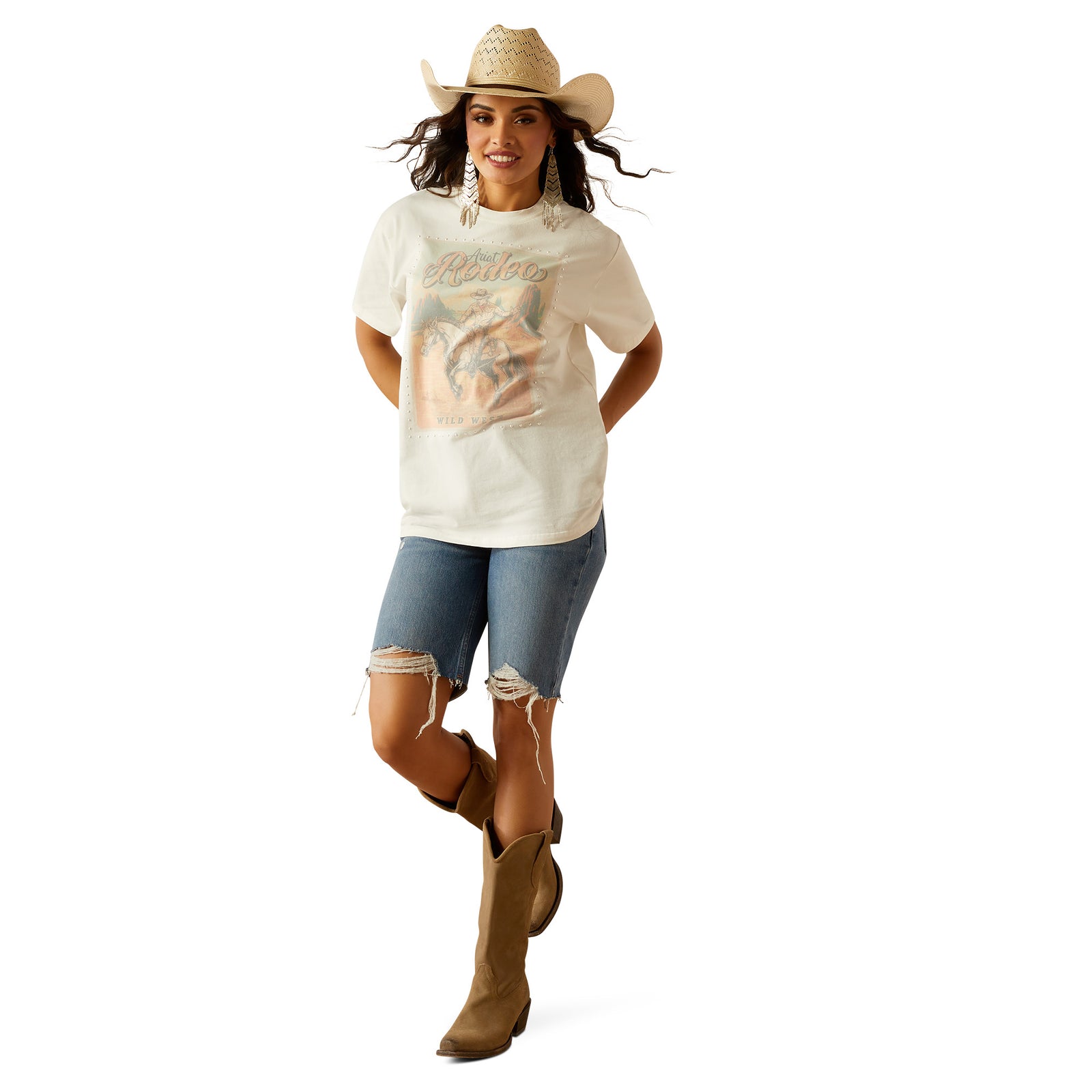 Ariat Women's Rodeo T-Shirt. Woman wearing a white t-shirt with a graphic design and a cowboy hat on a white background
