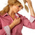 Ariat Women's Wrinkle Resistant Kirby Stretch L/S Western Shirt. Woman wearing a pink shirt, blue jeans, and a cowboy hat on a white background