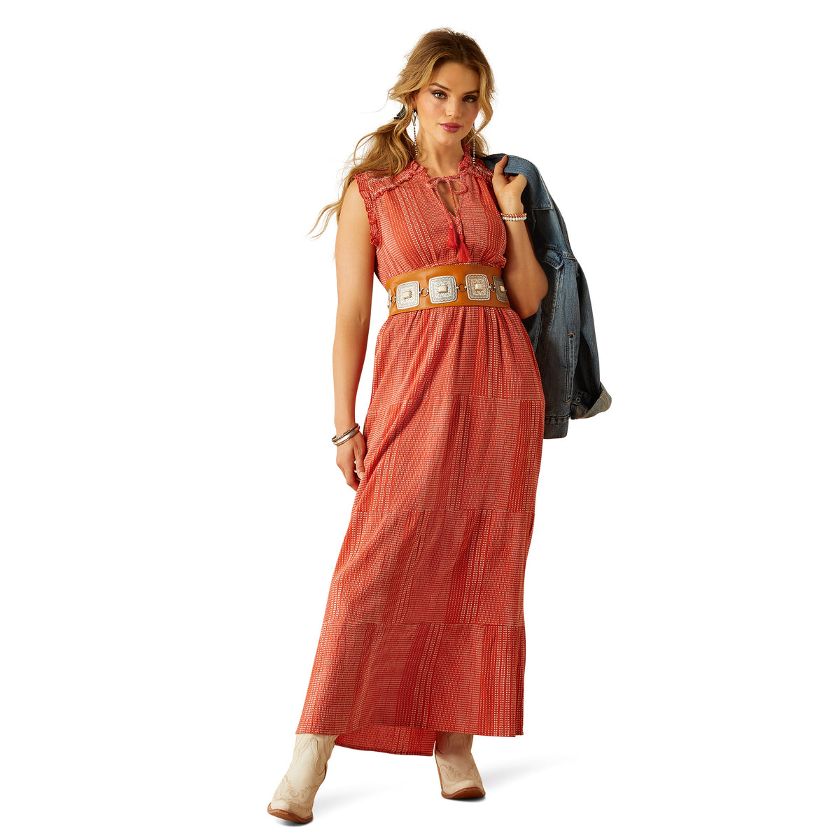 Ariat Women's Sunset State of Mind Dress. Woman wearing a long orange dress with a belt, holding a black bag on a white background