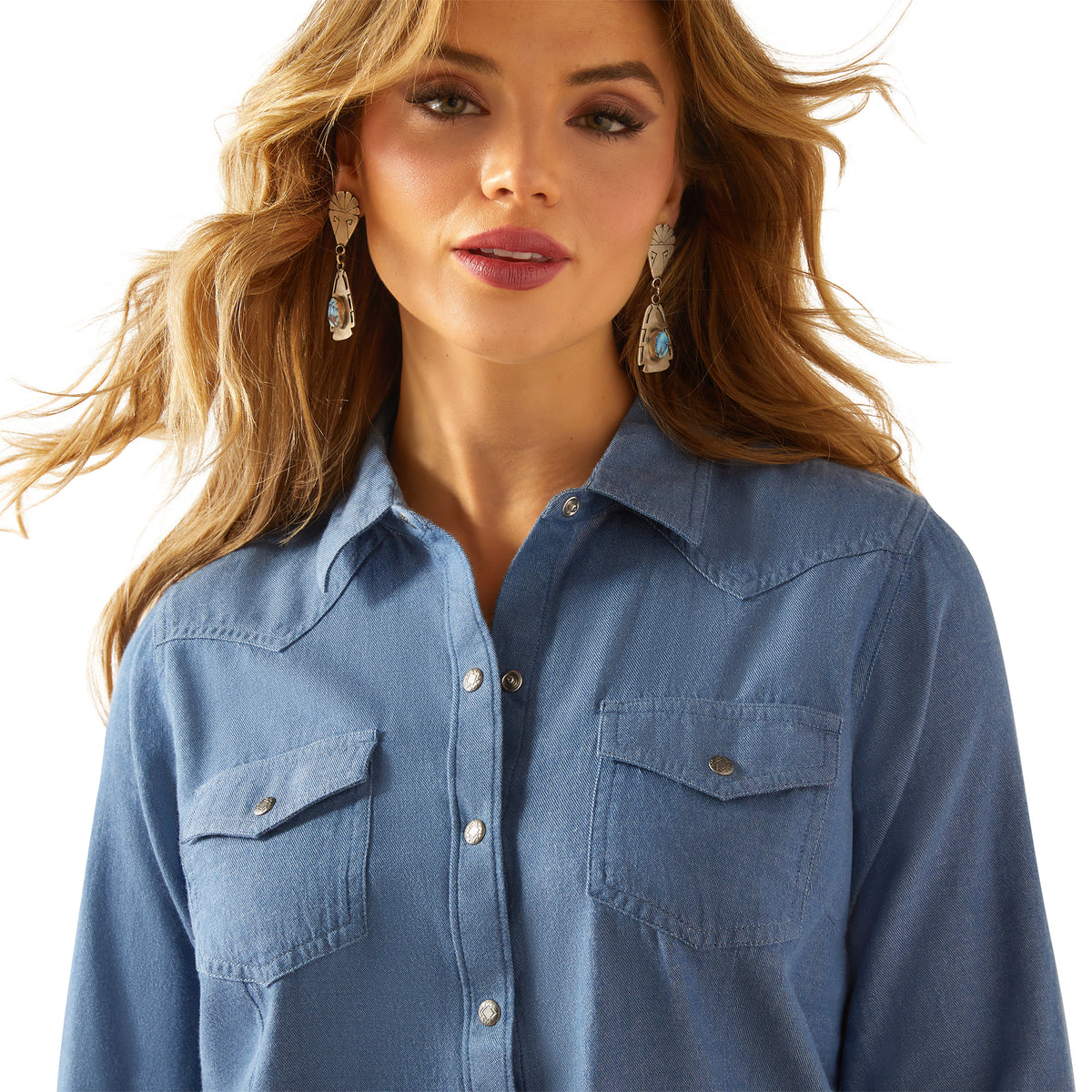 Ariat Women's Everyday Western Snap L/S Shirt. Woman wearing a blue denim shirt with a plain background
