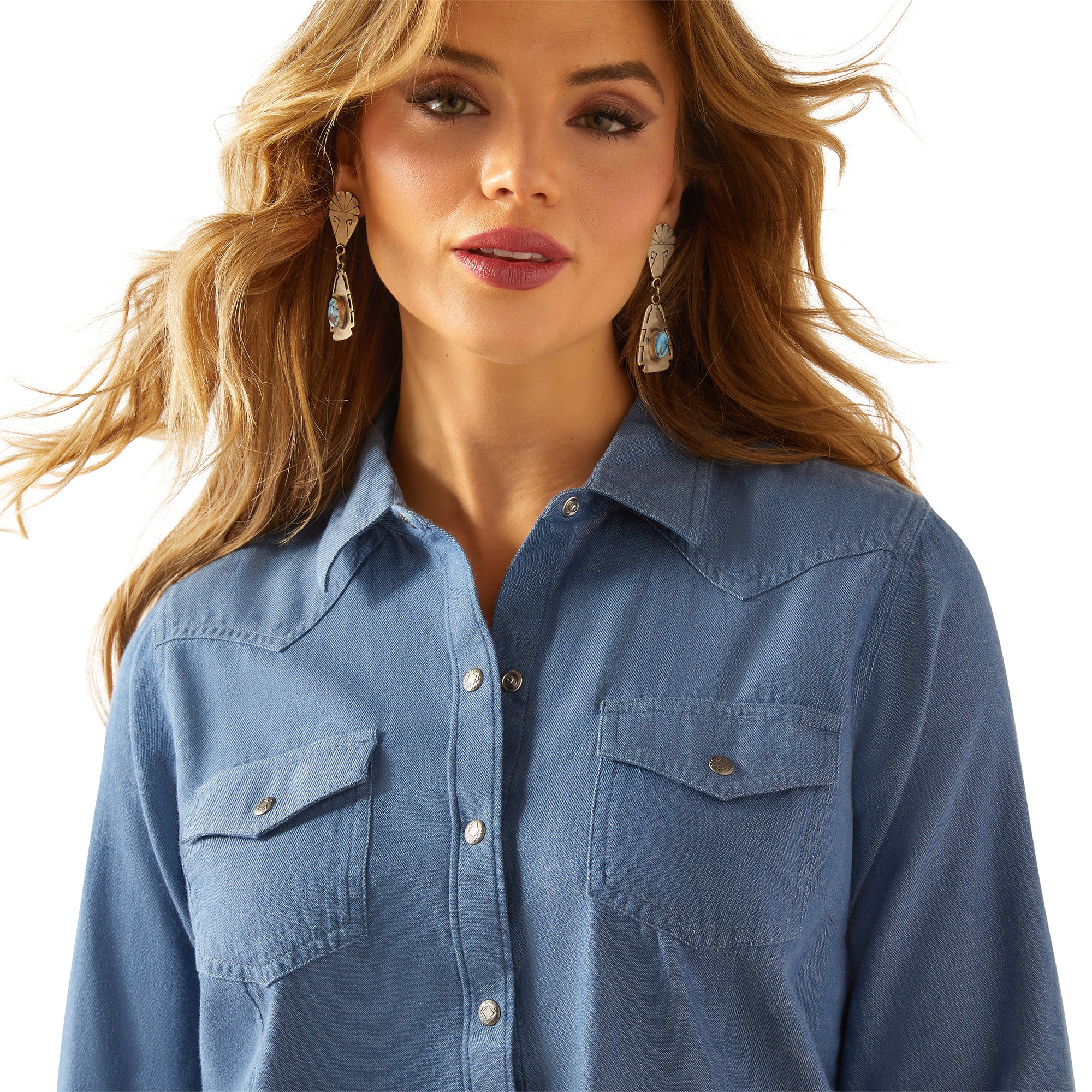 Ariat Women's Everyday Western Snap L/S Shirt. Woman wearing a blue denim shirt on a white background