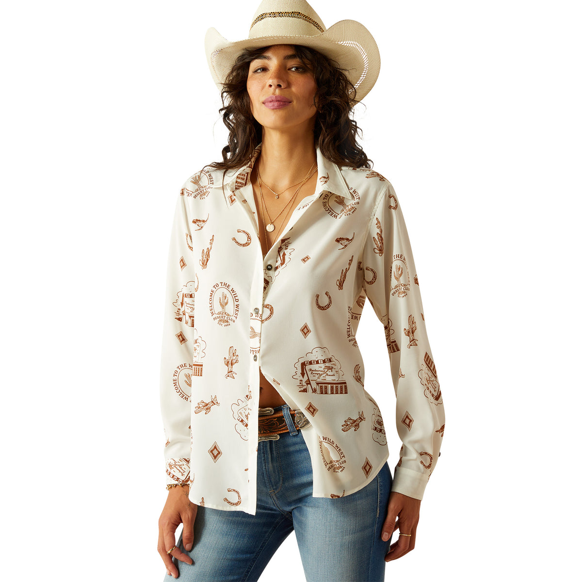 Ariat Women&#39;s Homestyle Button Up L/S Western Shirt. Woman wearing a white shirt with cowboy pattern and jeans on a white background