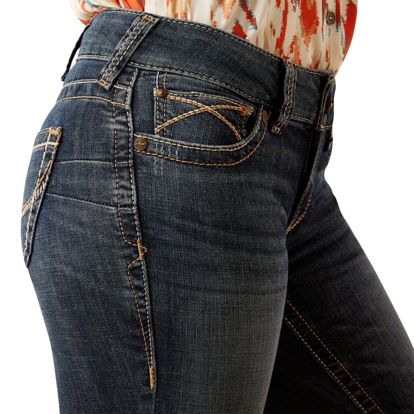 Ariat Women's Lilla Mid Rise Boot Cut Jean. Close-up of dark blue jeans with a white background