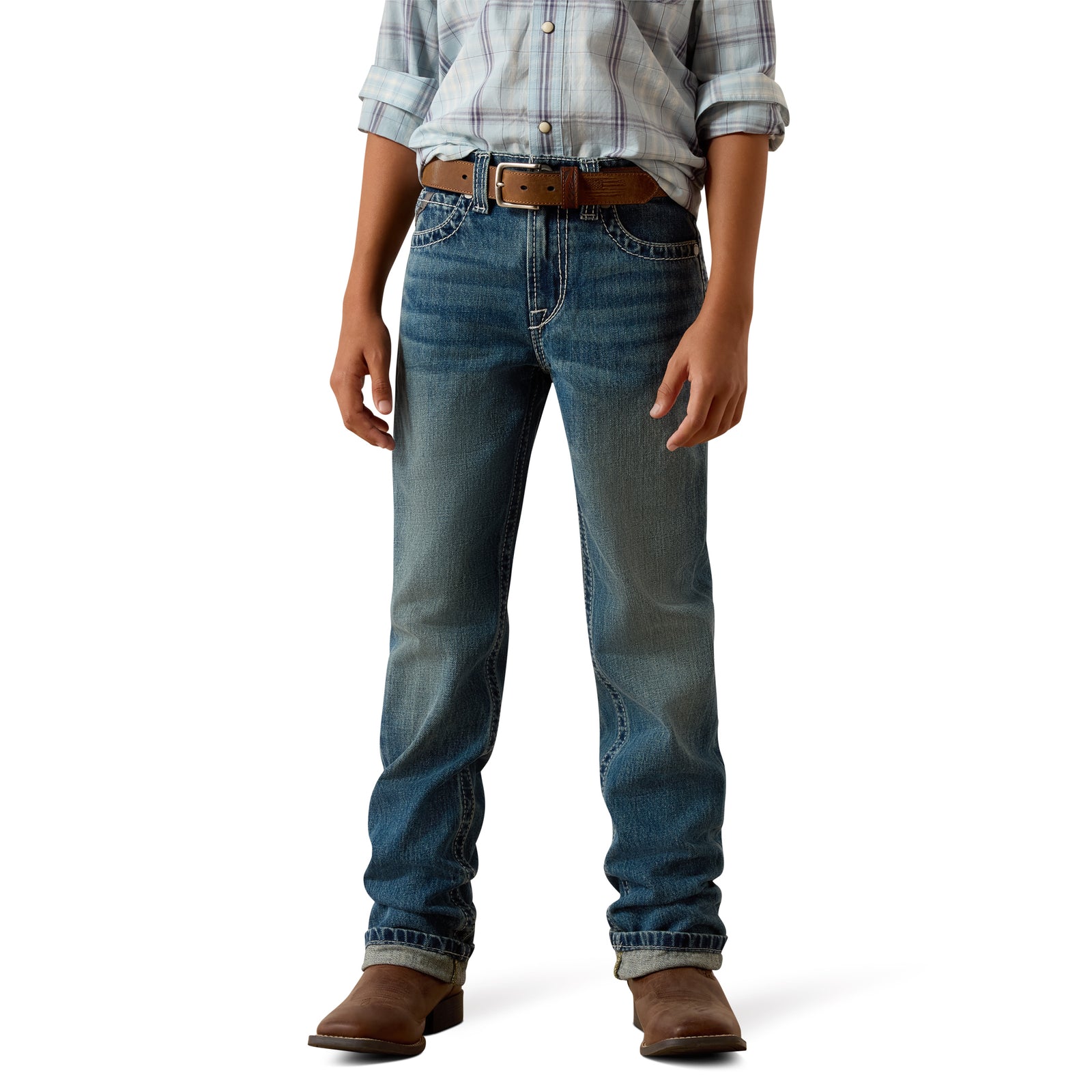 A person wearing a pair of medium-wash blue jeans with a brown belt, paired with a plaid button-up shirt and brown boots, shown from the waist down on a white studio background.
