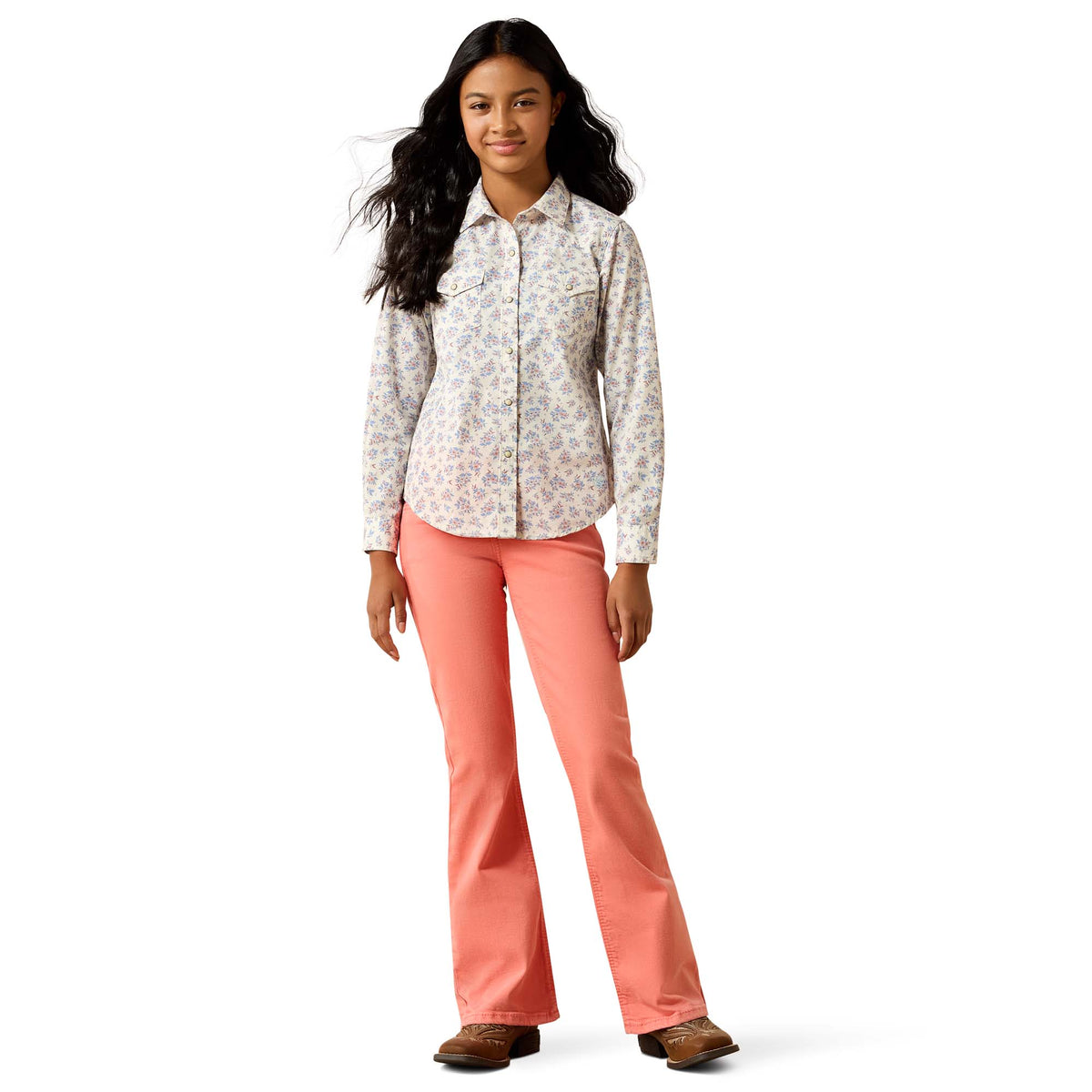 Woman wearing a patterned shirt and coral pants on a white background