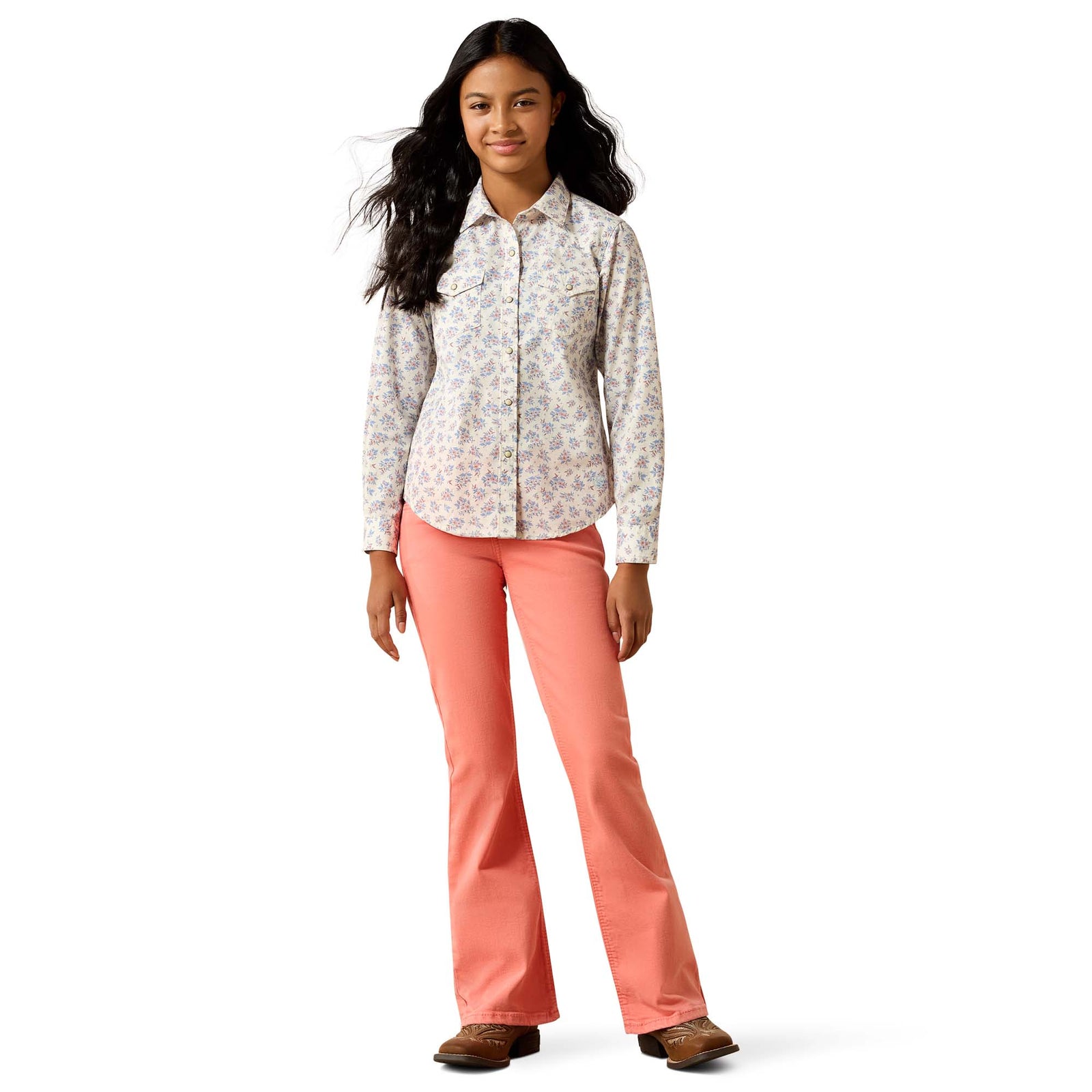 Woman wearing a patterned shirt and coral pants on a white background