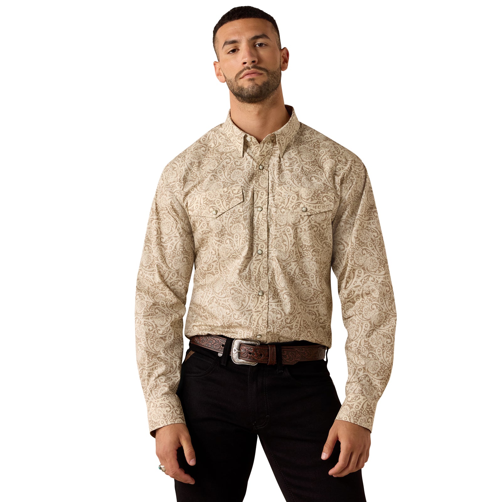 A man wearing a beige and brown paisley patterned long-sleeve western shirt with black pants, standing against a plain white background.