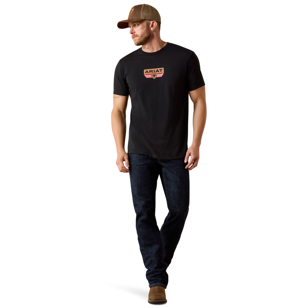 Man wearing a black t-shirt with a logo and dark jeans on a white background