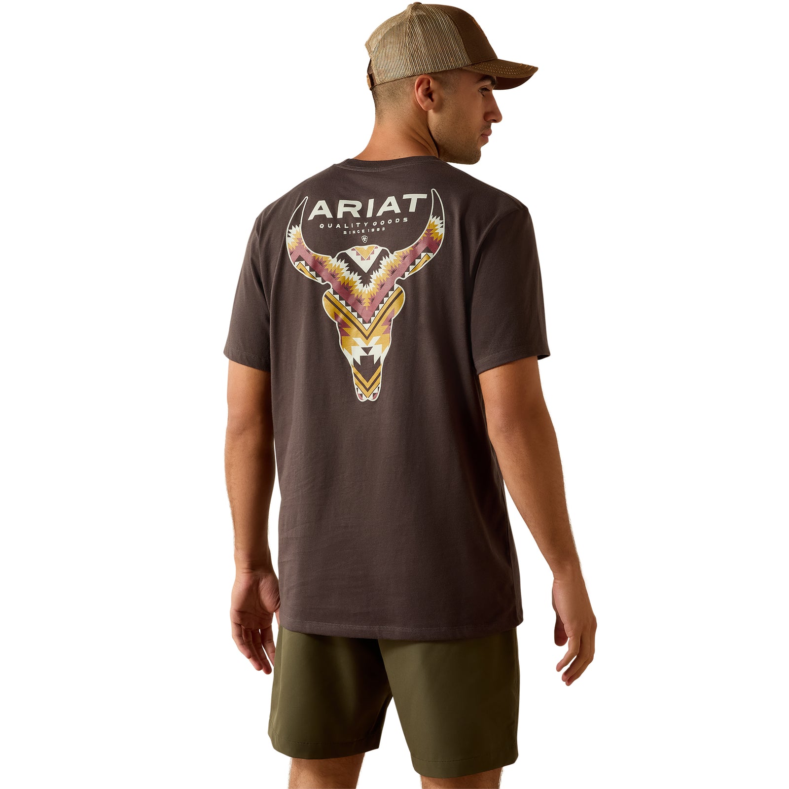 Man wearing an Ariat t-shirt with a bull skull design on the back, standing against a white background.