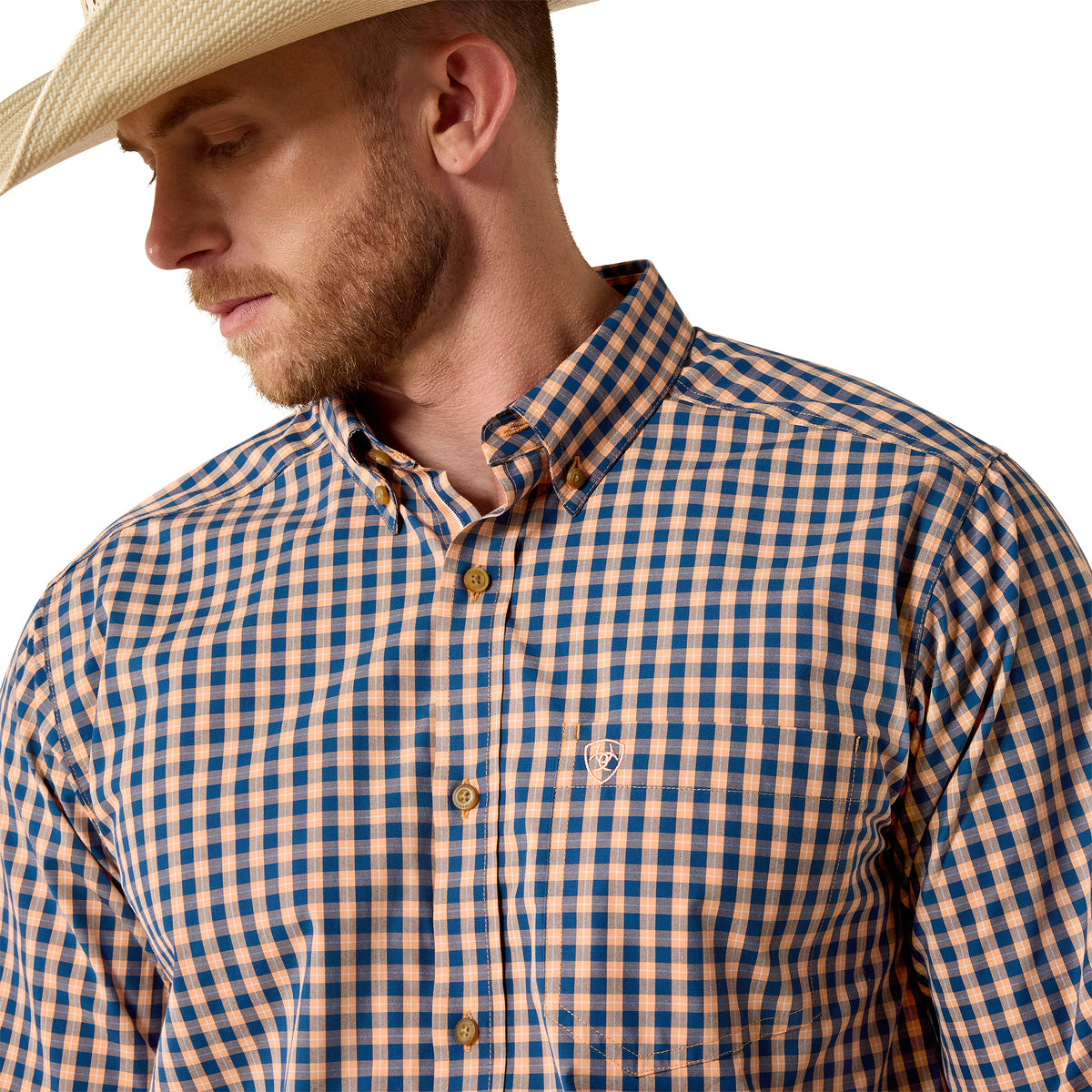 A man wearing a blue and tan gingham button-down shirt and a straw cowboy hat, shown in a close-up profile view against a white background.