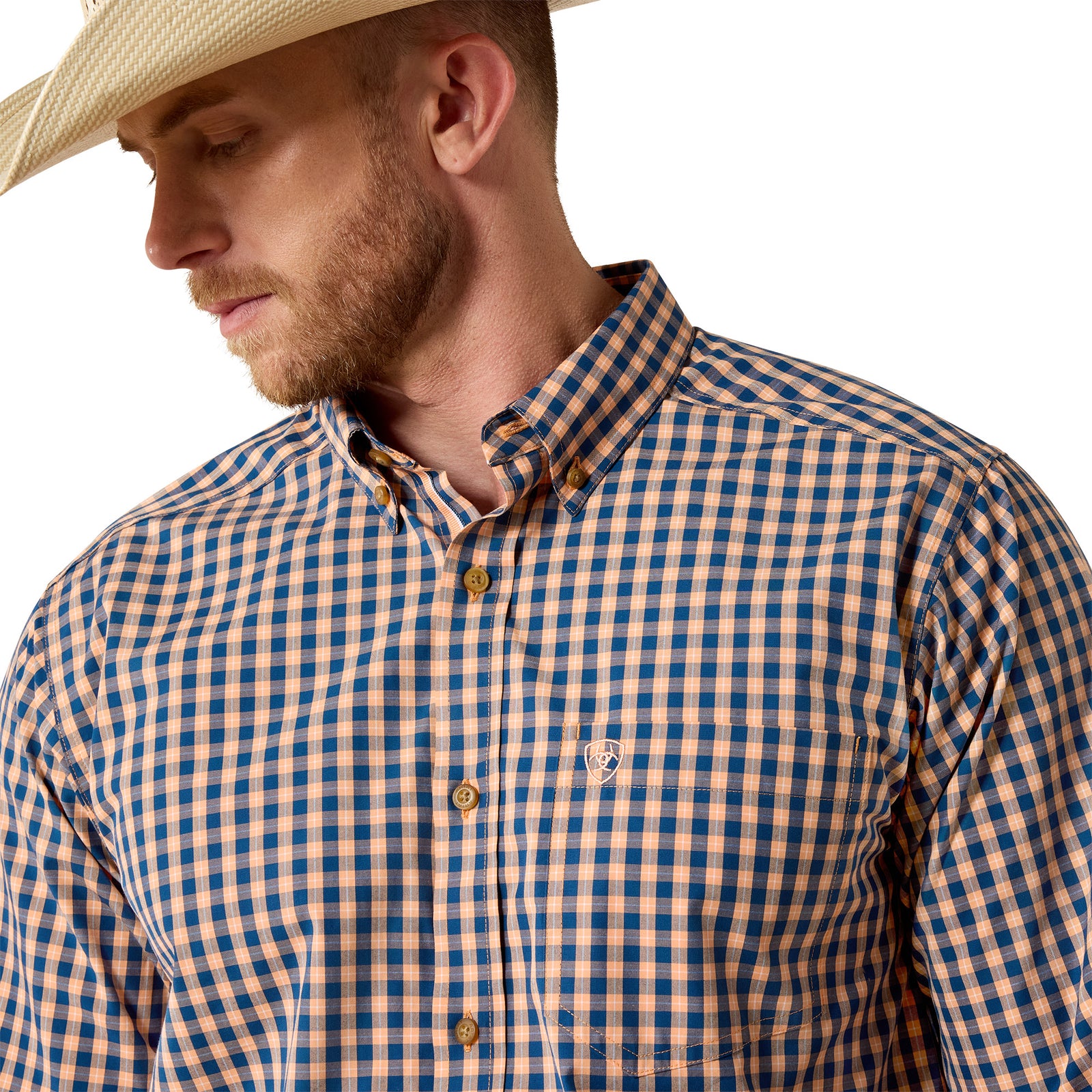 A man wearing a blue and tan gingham button-down shirt and a straw cowboy hat, shown in a close-up profile view against a white background.