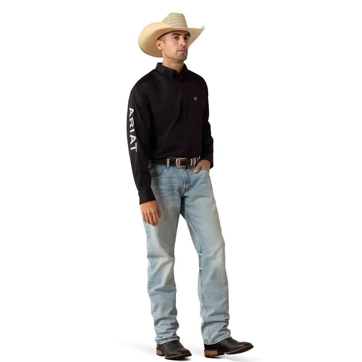 Man wearing a black Ariat shirt, light blue jeans, and a cowboy hat on a white background
