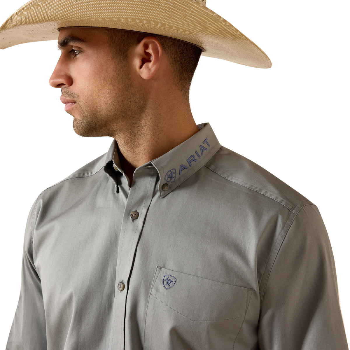 Man wearing a gray shirt with 'Ariat' branding and a straw hat on a white background