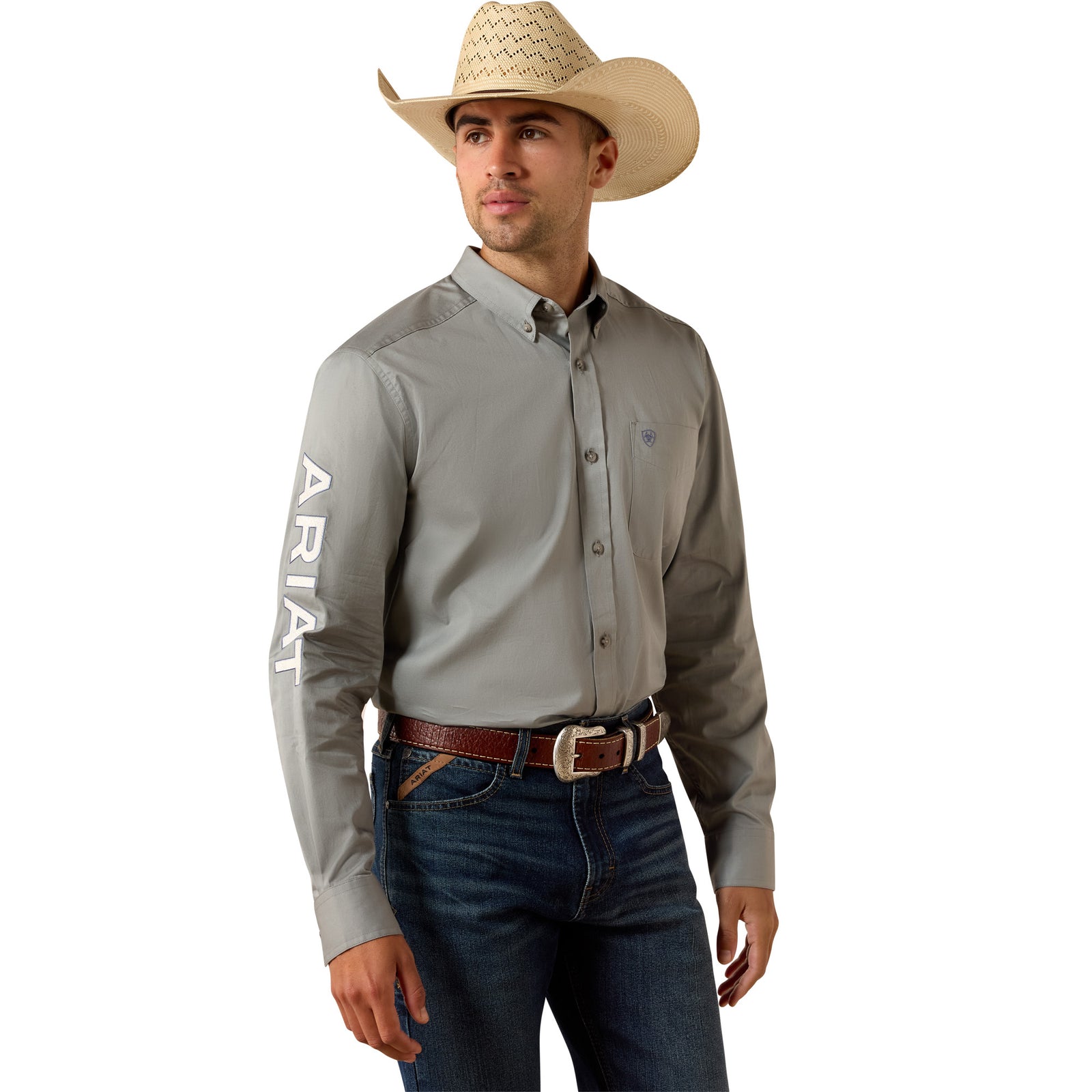 Man wearing a gray Ariat shirt, blue jeans, and a cowboy hat on a white background