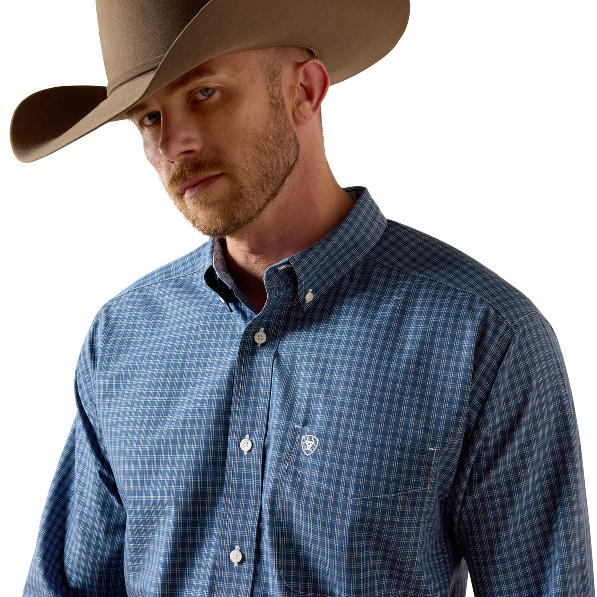 A man wearing a brown cowboy hat and a blue and gray checkered button-down shirt, shown from the chest up against a plain white background.
