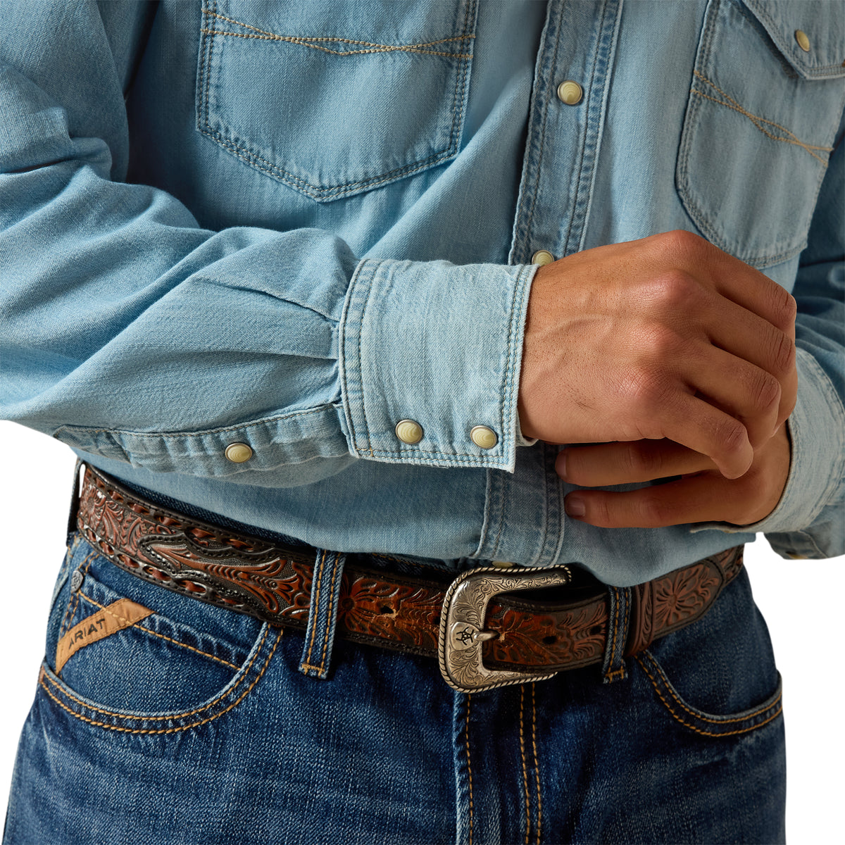 Close-up of a person wearing a light blue denim shirt and jeans with a brown belt.