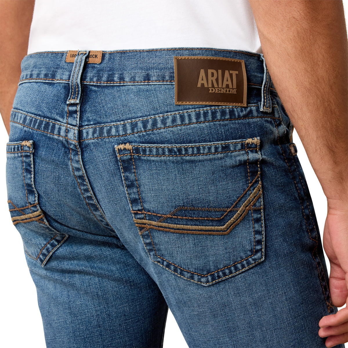 Close-up of blue jeans with Ariat denim label on a white background
