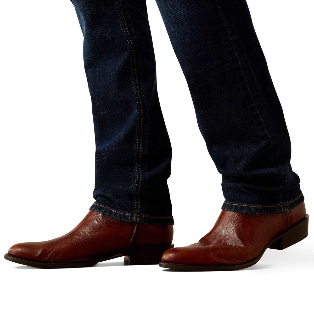 Brown leather shoes worn with dark blue jeans on a white background