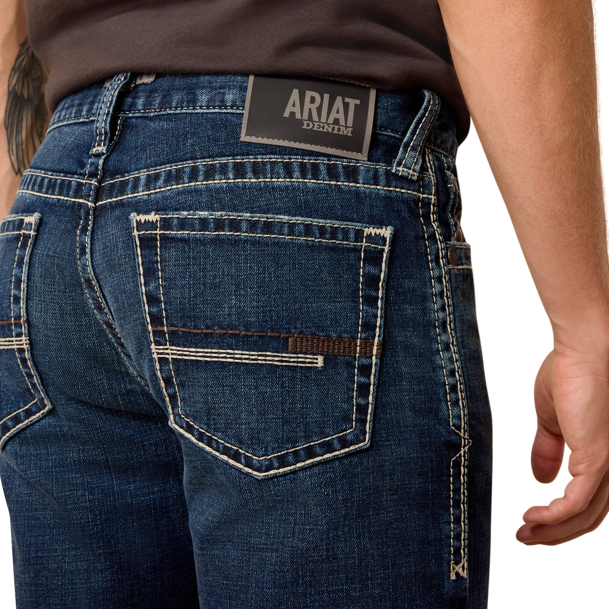 Close-up of blue jeans with Ariat denim label on a white background
