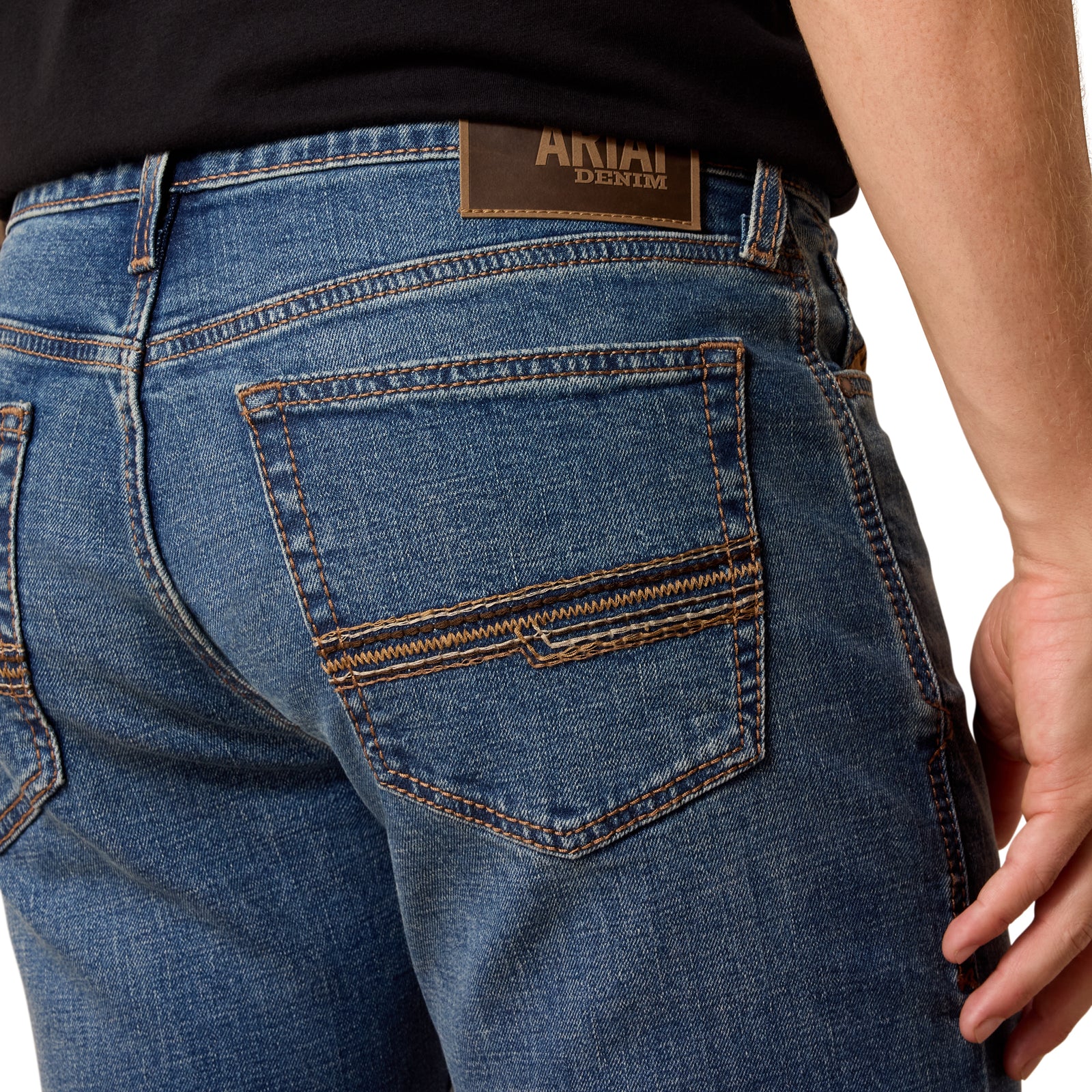 Close-up of blue jeans with a brand label on the back pocket against a neutral background