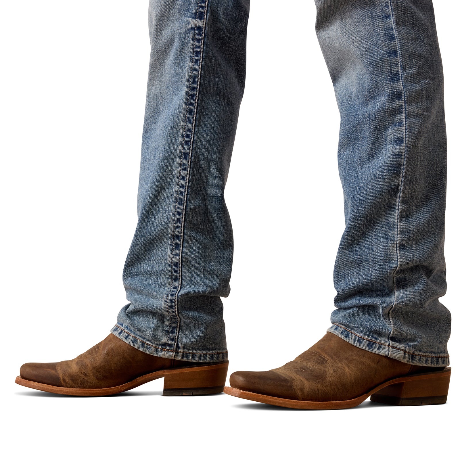 Brown cowboy boots worn with blue jeans on a white background