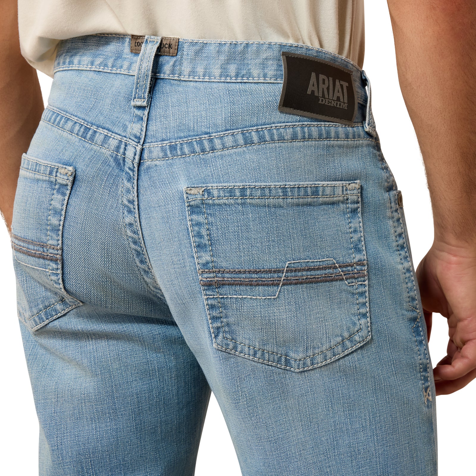Close-up of blue jeans with Ariat logo on a white background