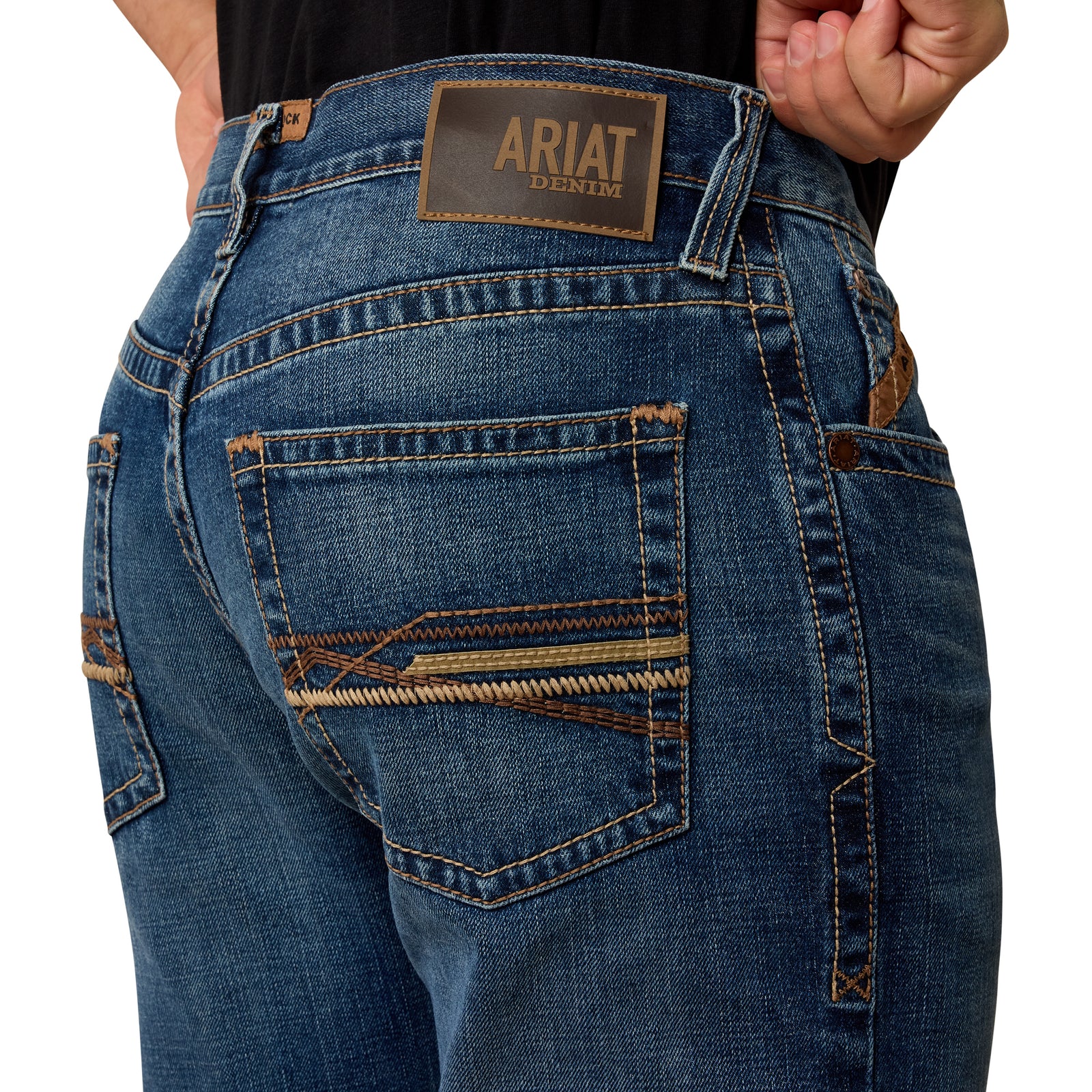 Close-up of blue jeans with Ariat logo on the back pocket against a white background