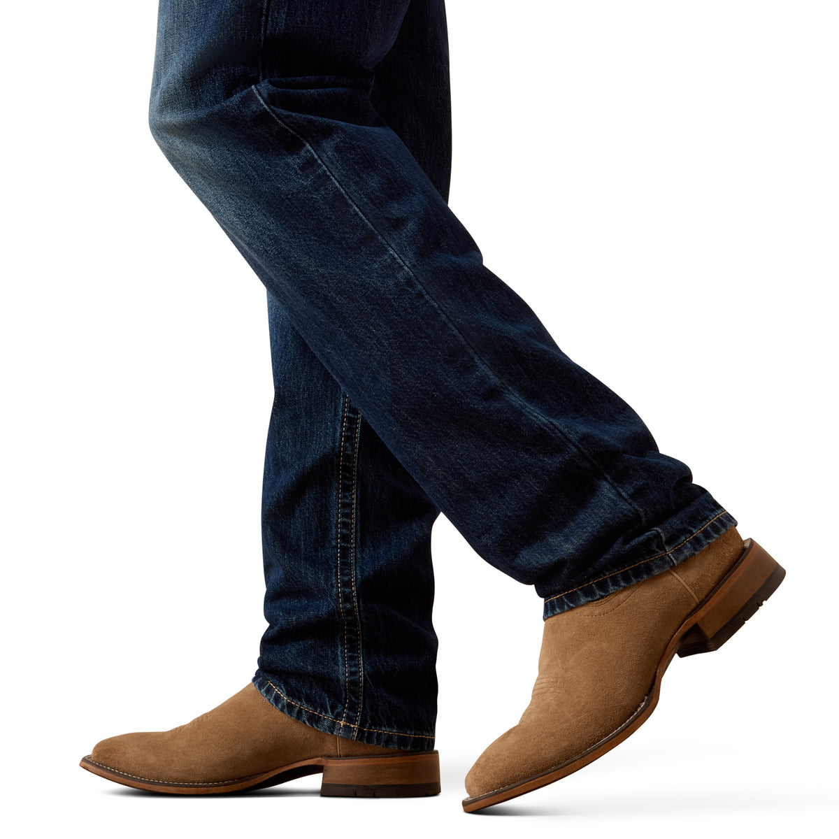 A close-up of a person's legs wearing dark blue denim jeans and tan suede cowboy boots against a plain white background.