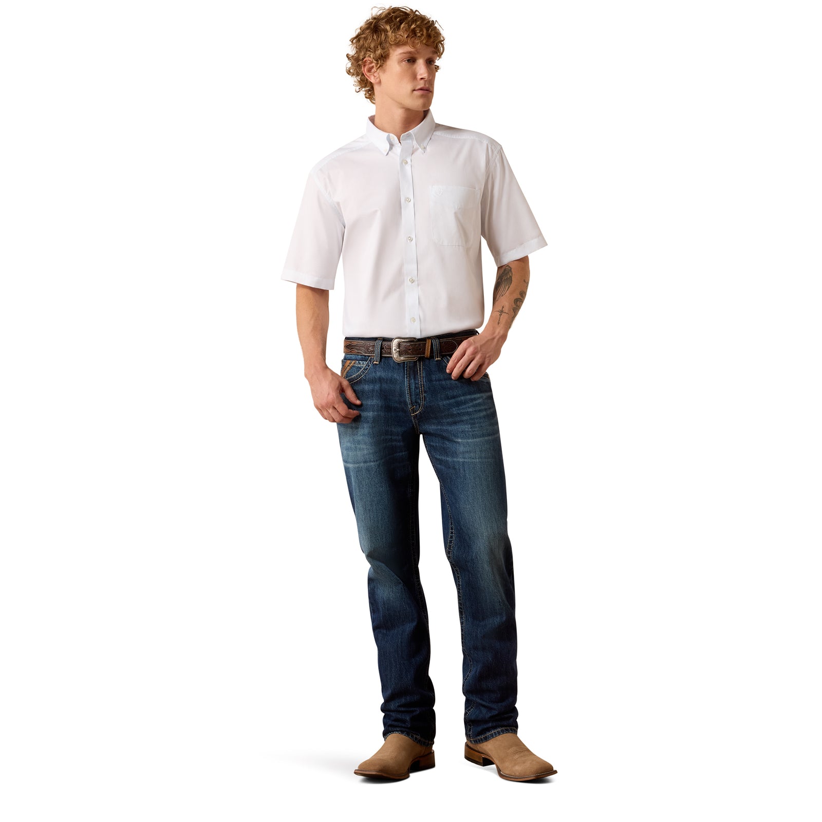 A man modeling a white short-sleeve button-down shirt, dark blue jeans, a brown belt, and brown boots against a plain white background.