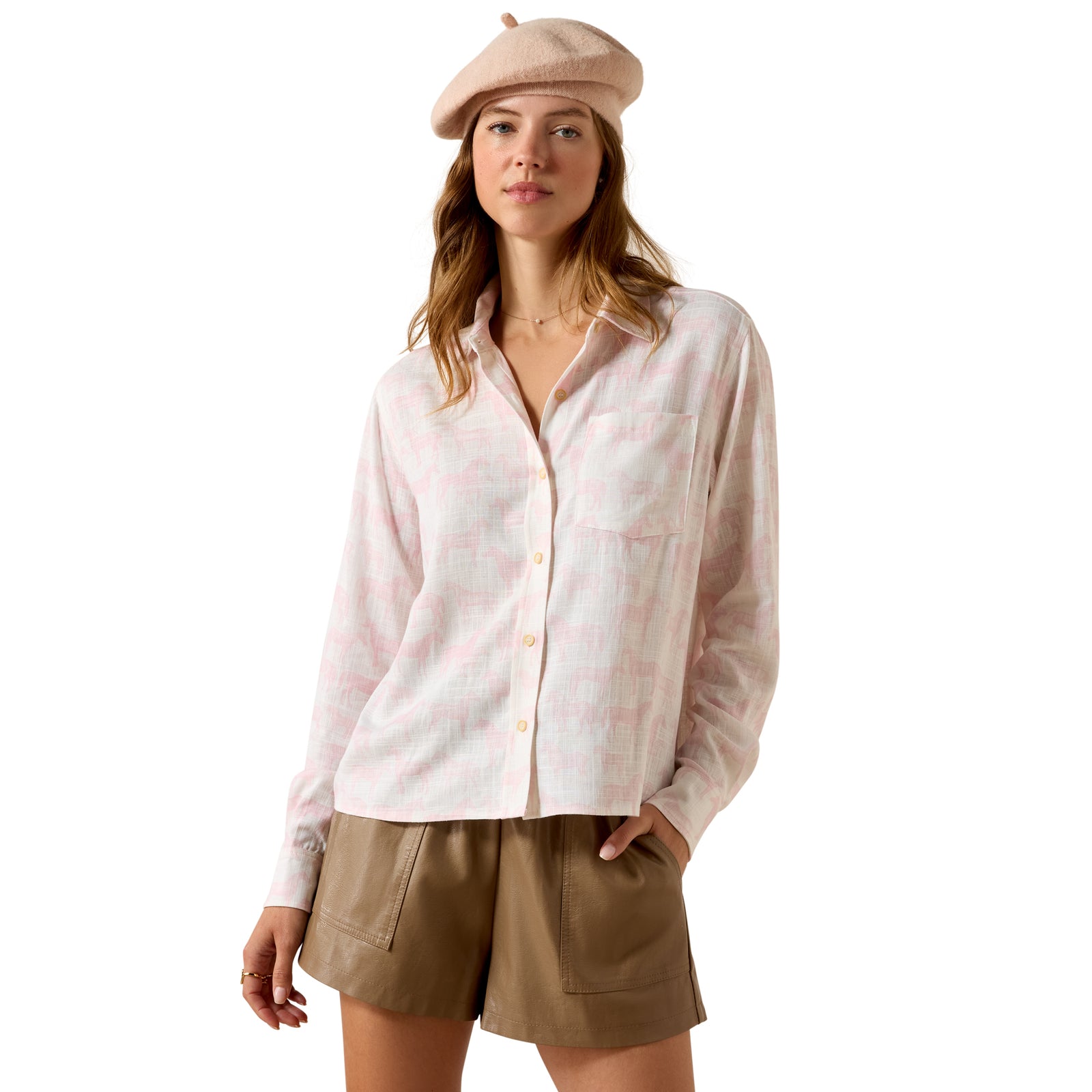 Woman wearing a light pink button-up shirt and beige shorts on a white background