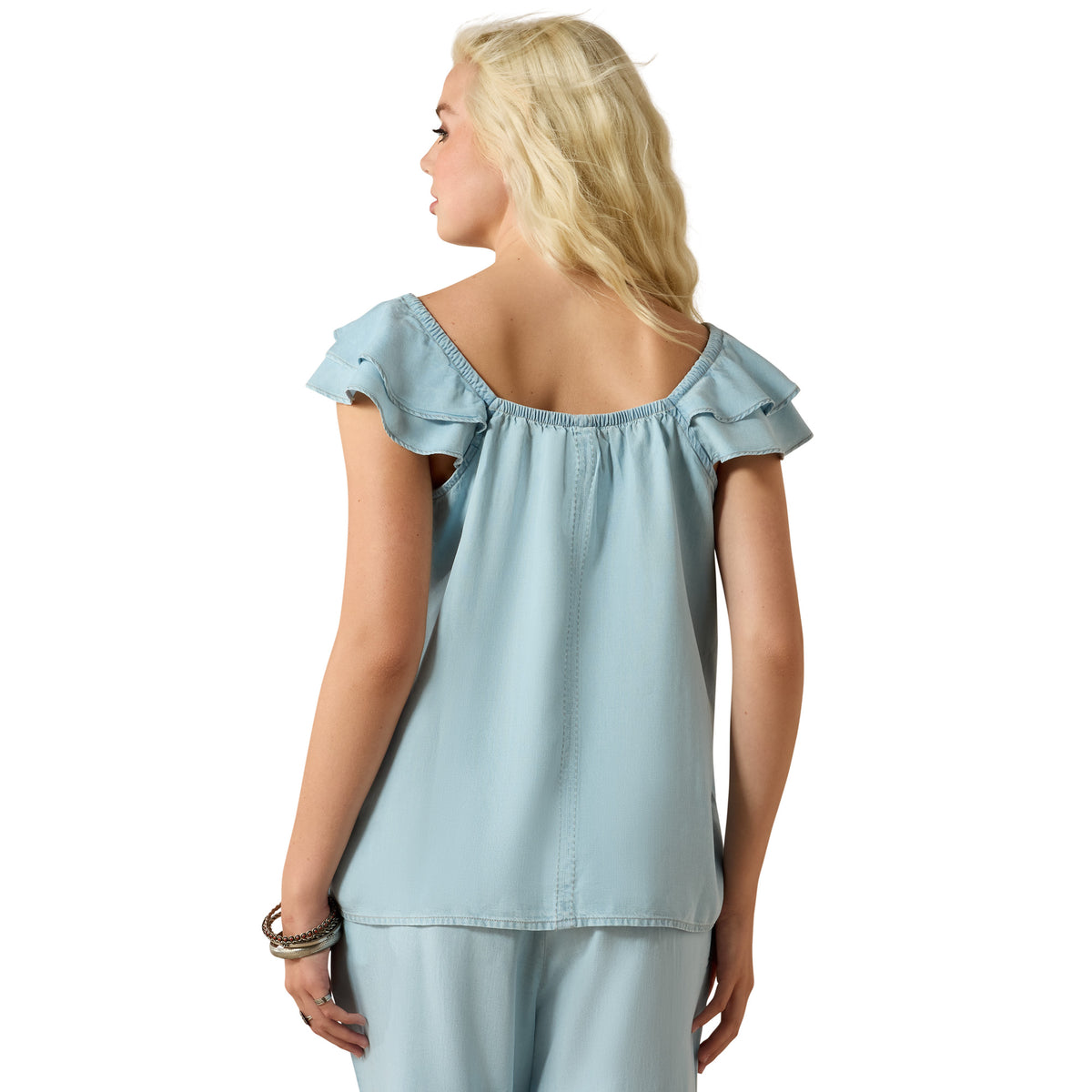 Woman wearing a light blue top with ruffled shoulders on a white background