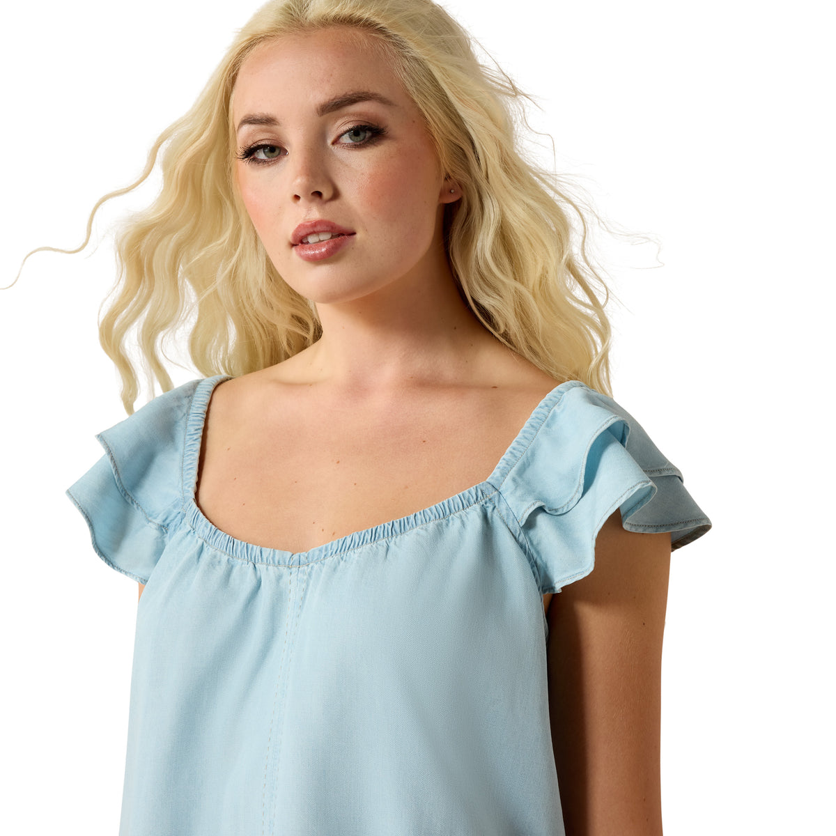 Woman wearing a light blue top with ruffled shoulders on a white background