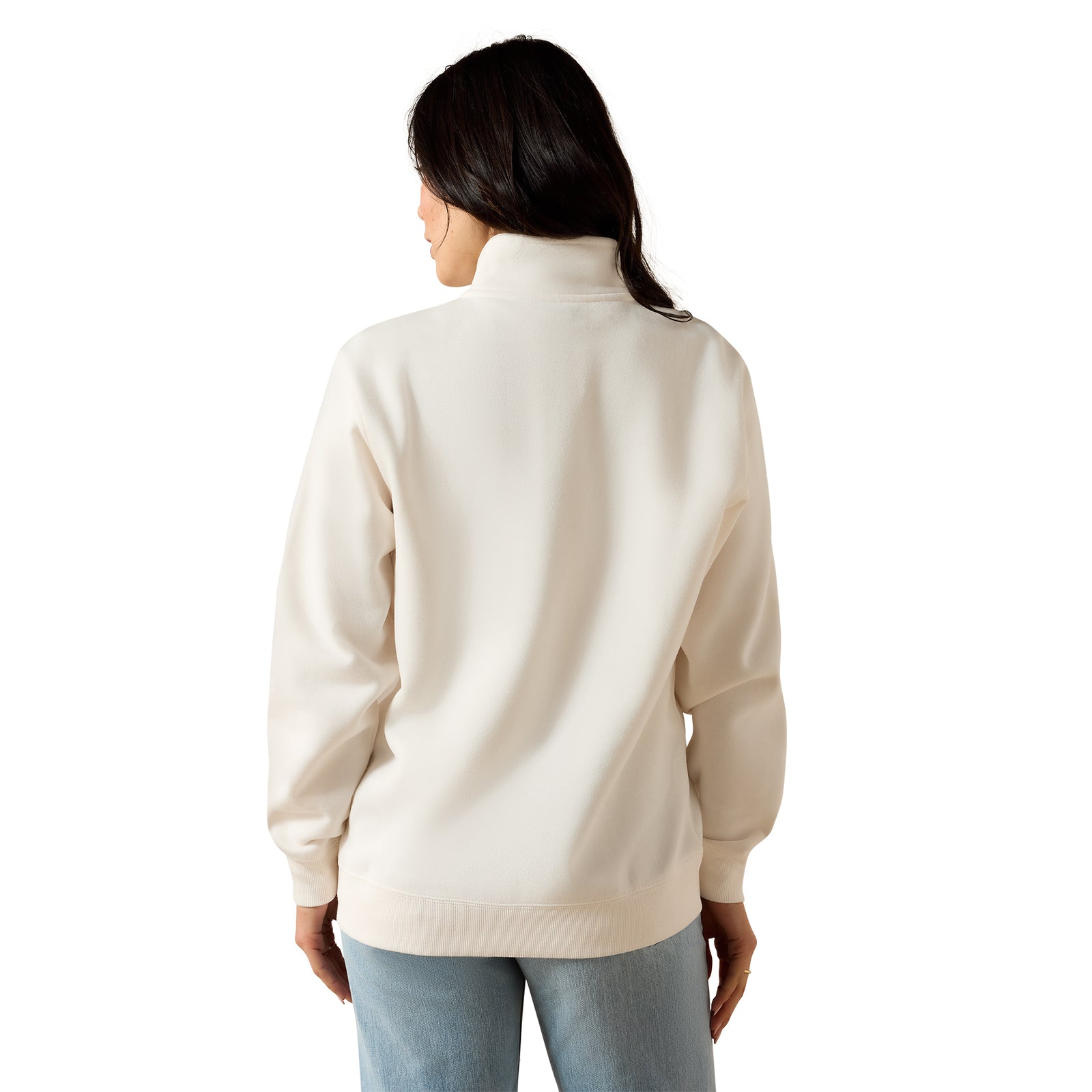 A woman viewed from the back wearing a cream-colored mock neck sweatshirt and light blue jeans against a plain white background.