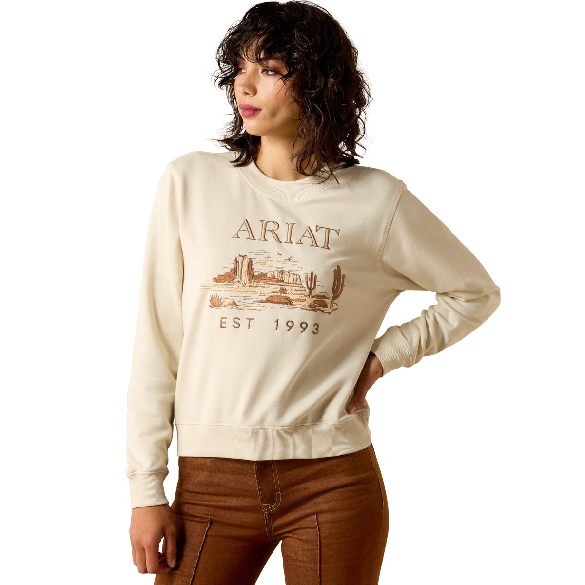 Woman wearing a beige Ariat sweatshirt on a white background