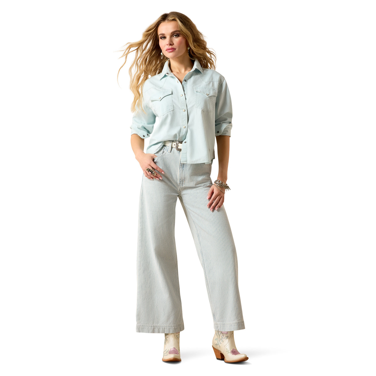 Woman wearing a light blue shirt and white pants on a white background